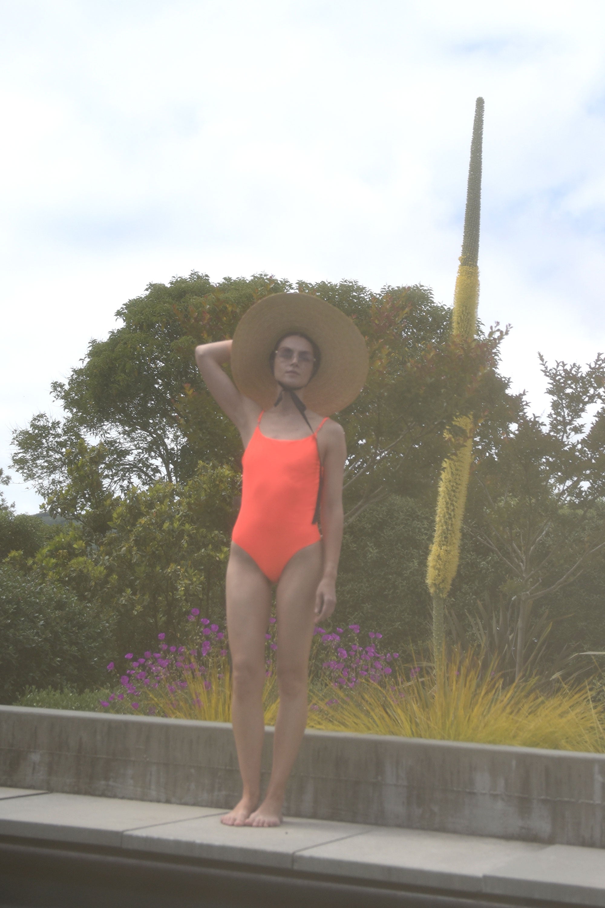 Editorial image of the coral Italian regenerated nylon Kamperett Selwood One Piece.