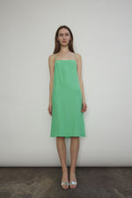 Front view of a model wearing the celadon silk charmeuse Kamperett Short Slip, a midi slip with fixed spaghetti straps.