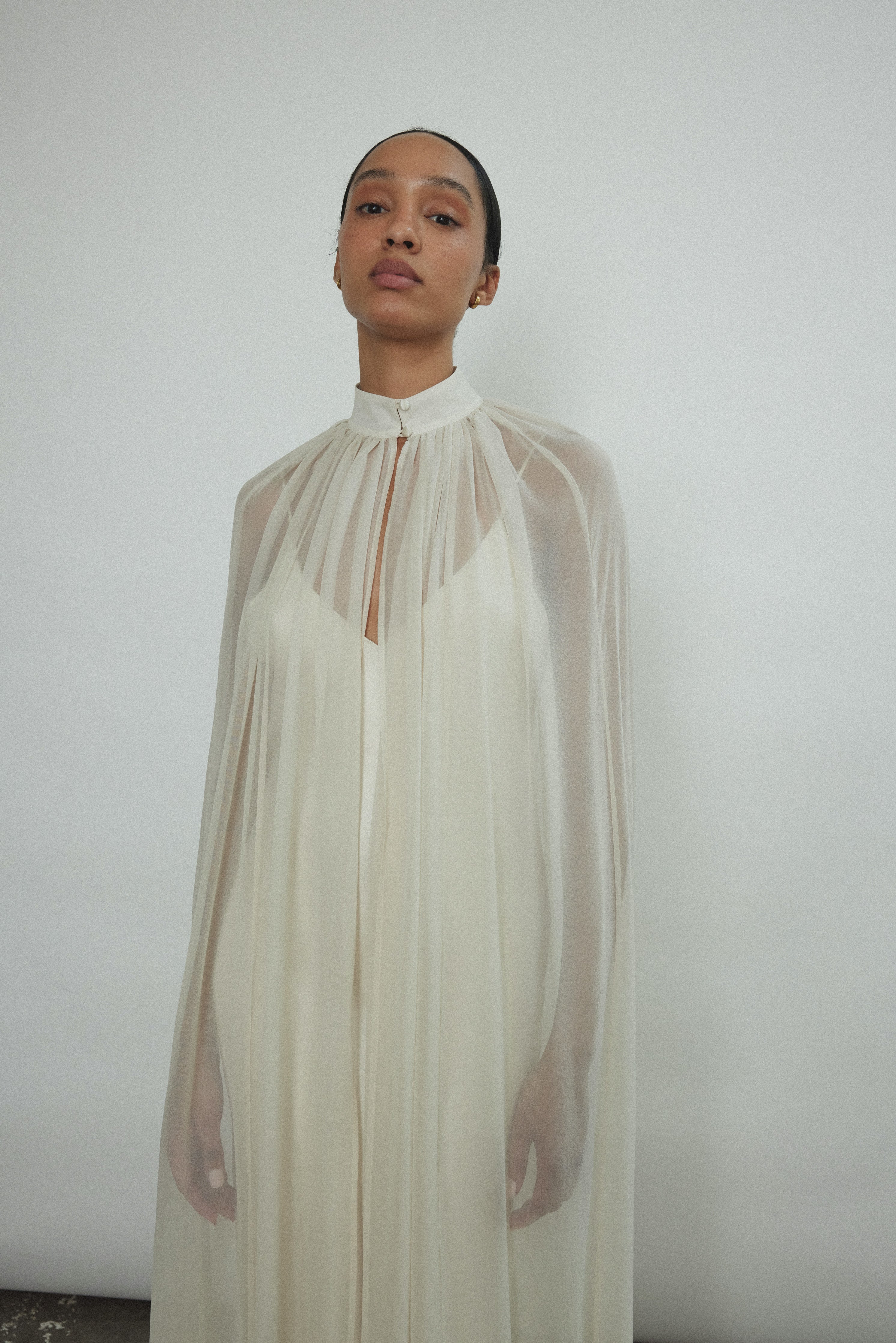 Detail of the self-button collar closure on the ivory silk chiffon Kamperett Choker Cape.