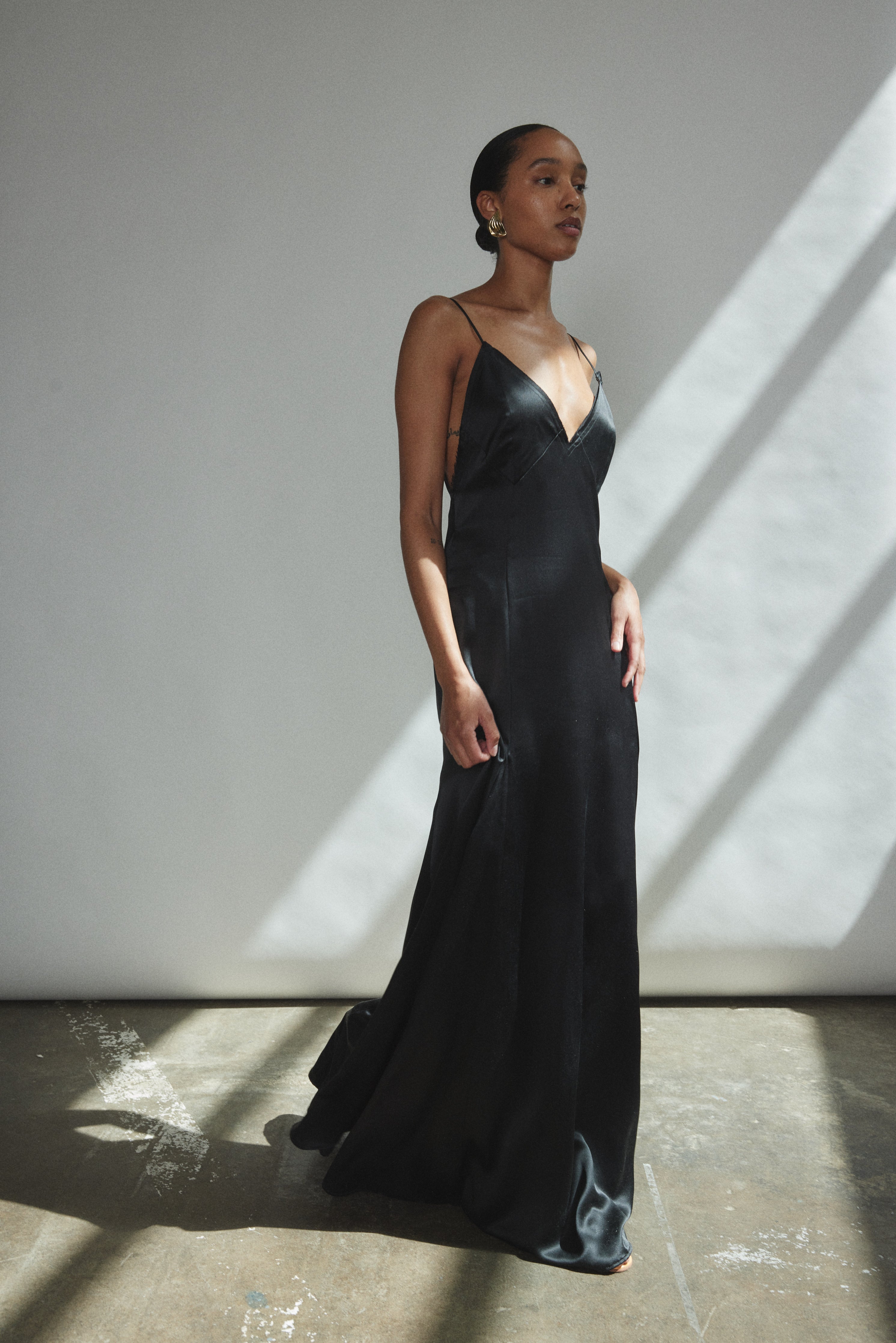 Angled view of the black silk charmeuse Kamperett Simone Slip Dress.