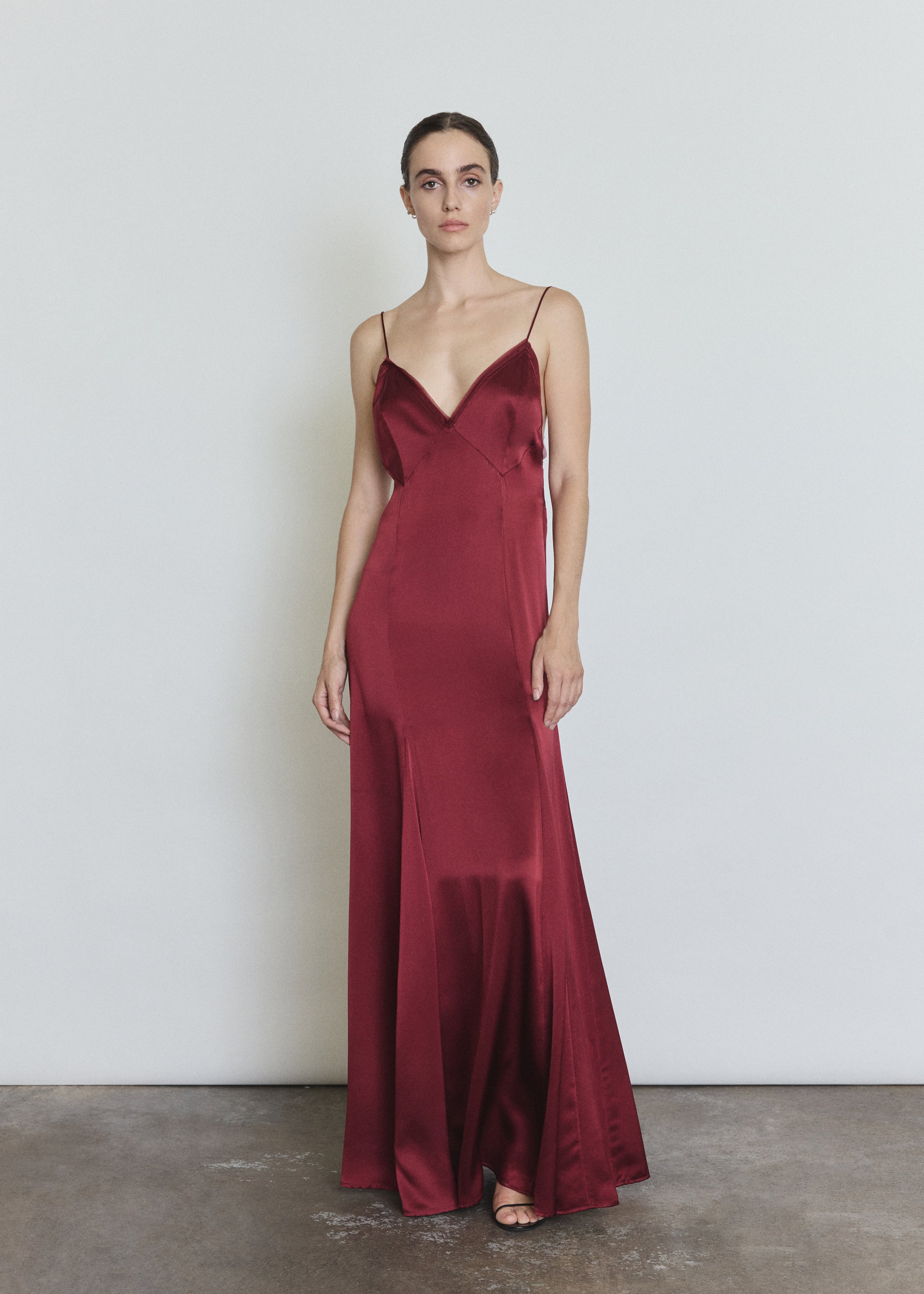 Front view of a model wearing the bordeaux silk charmeuse Kamperett Simone Slip Dress, a deco-inspired slip with V neck and corded straps.