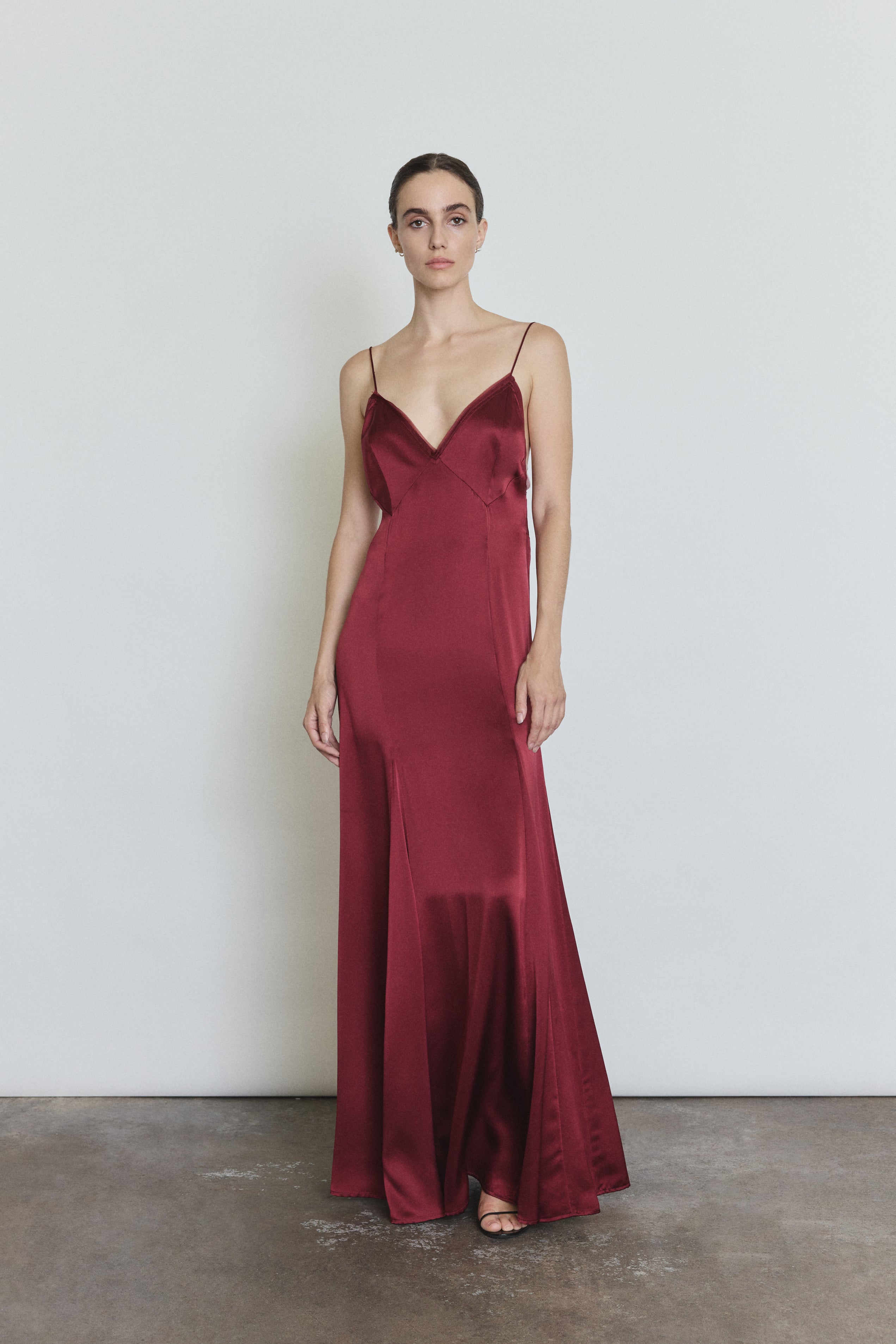Front view of a model wearing the bordeaux silk charmeuse Kamperett Simone Slip Dress, a deco-inspired slip with V neck and corded straps.