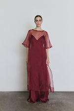 Model wearing the bordeaux Kamperett Simone Slip Dress layered under the Thea Sheath Dress in Bordeaux.