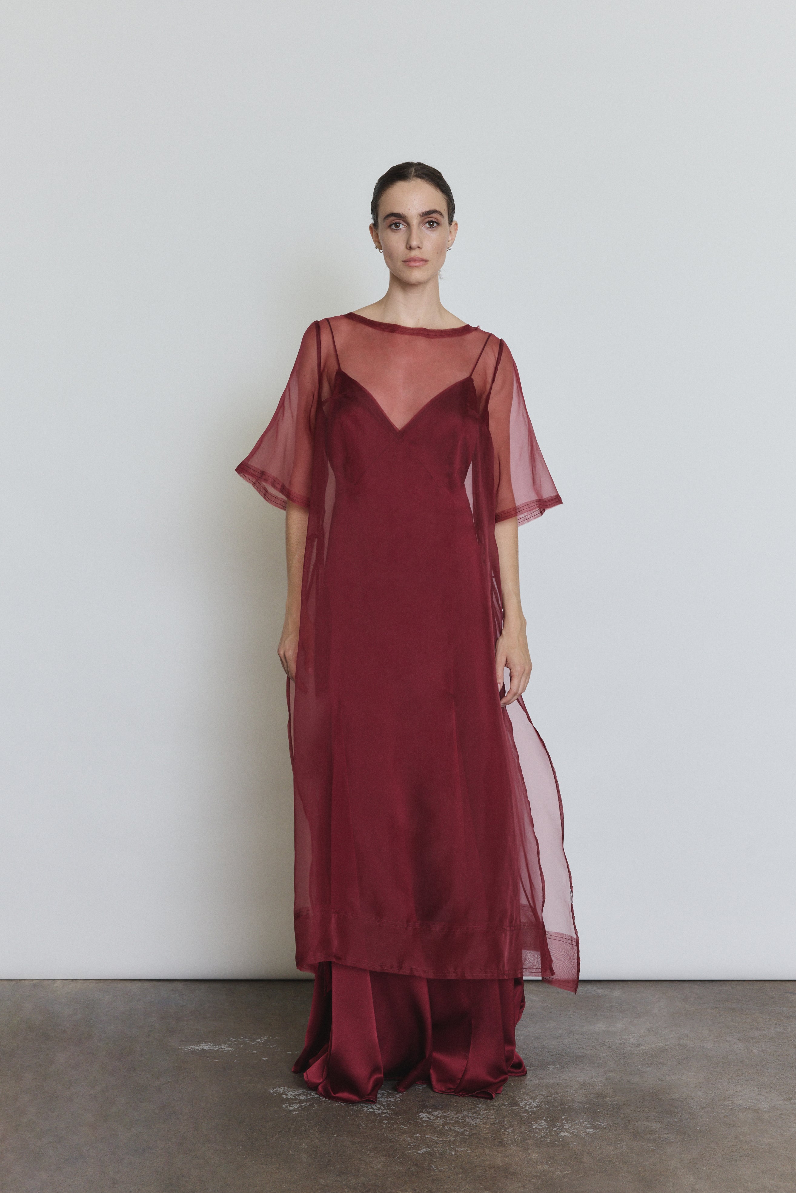 Model wearing the bordeaux Kamperett Simone Slip Dress layered under the Thea Sheath Dress in Bordeaux.