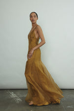 Editorial portrait of a model in the brass silk charmeuse Kamperett Simone Slip Dress.