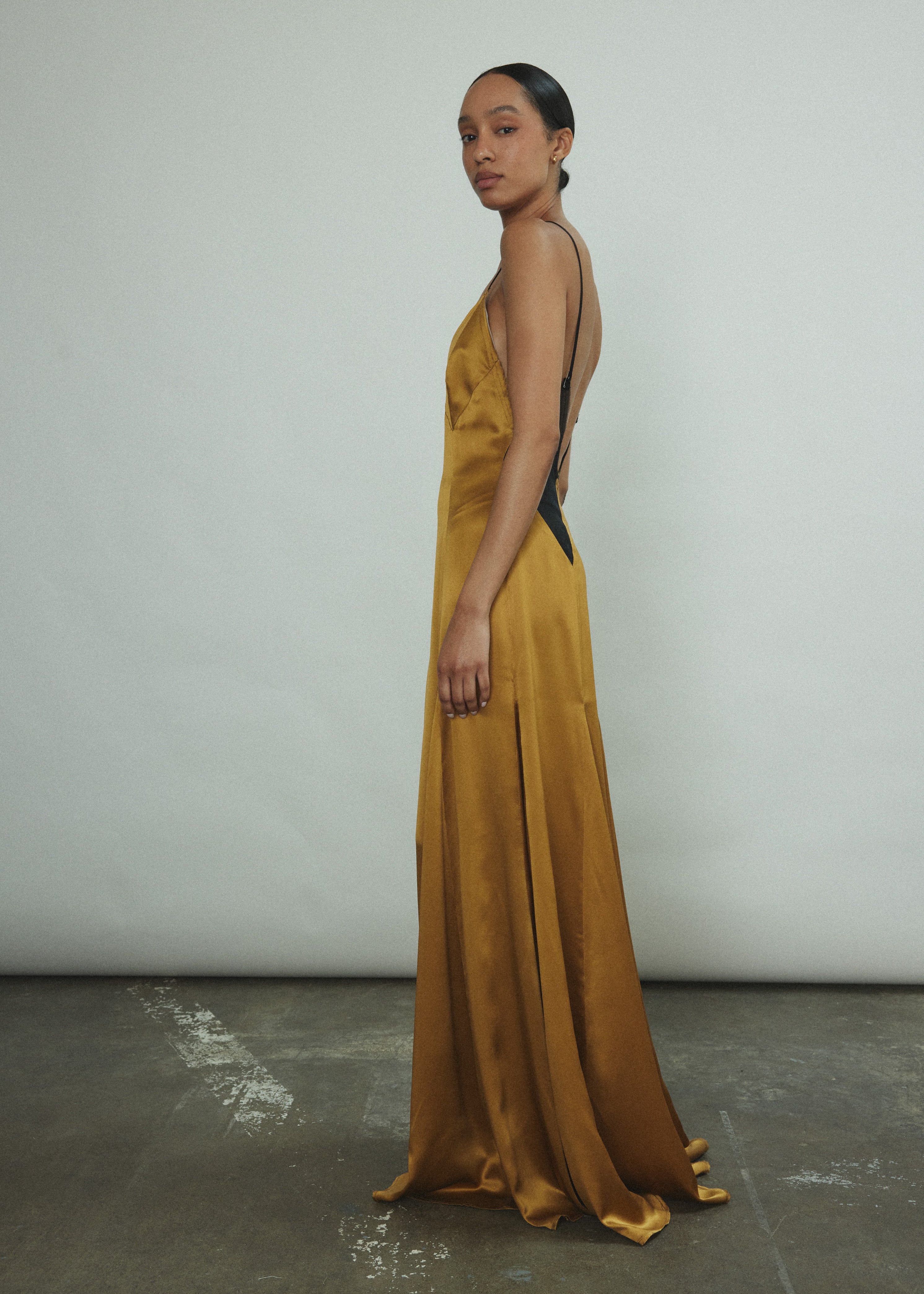 Side view of the brass silk charmeuse Kamperett Simone Slip Dress.
