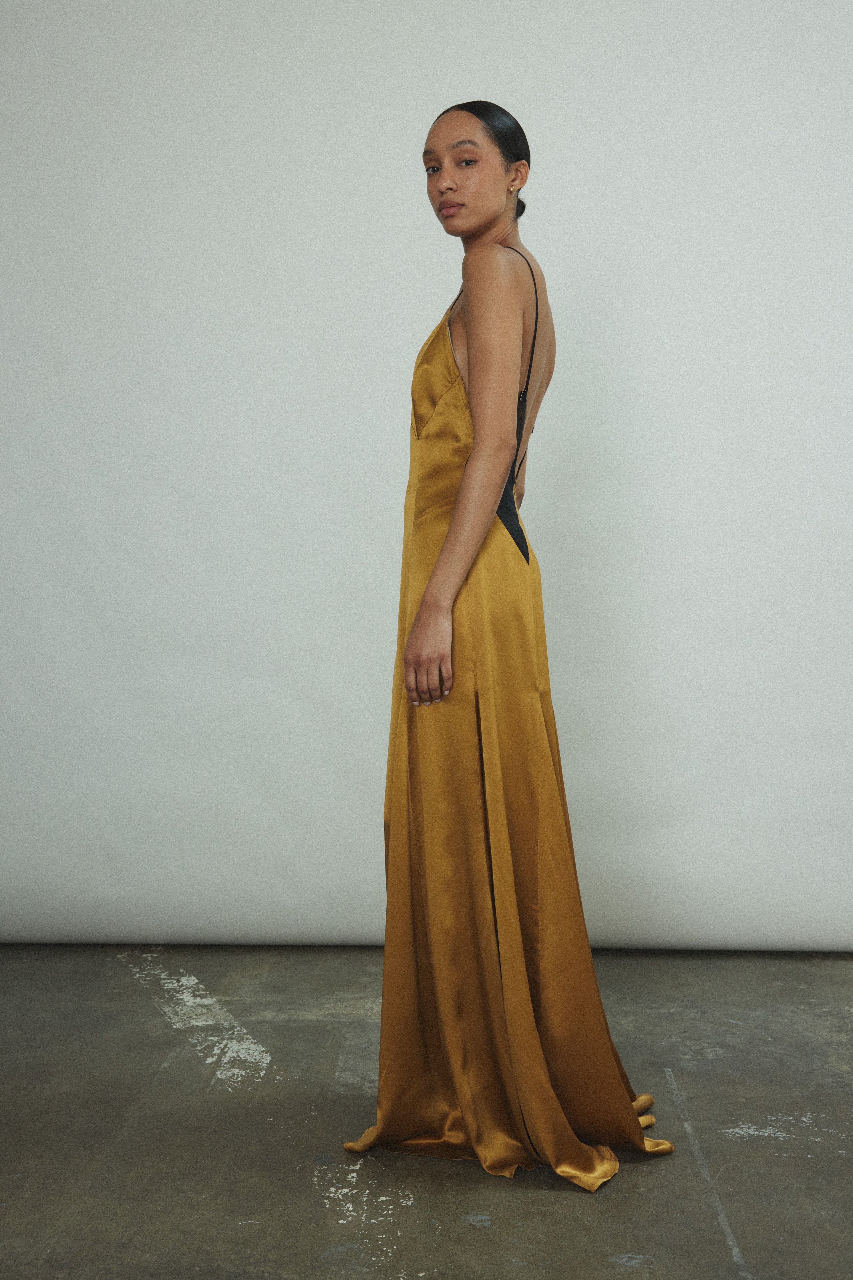 Side view of the brass silk charmeuse Kamperett Simone Slip Dress.