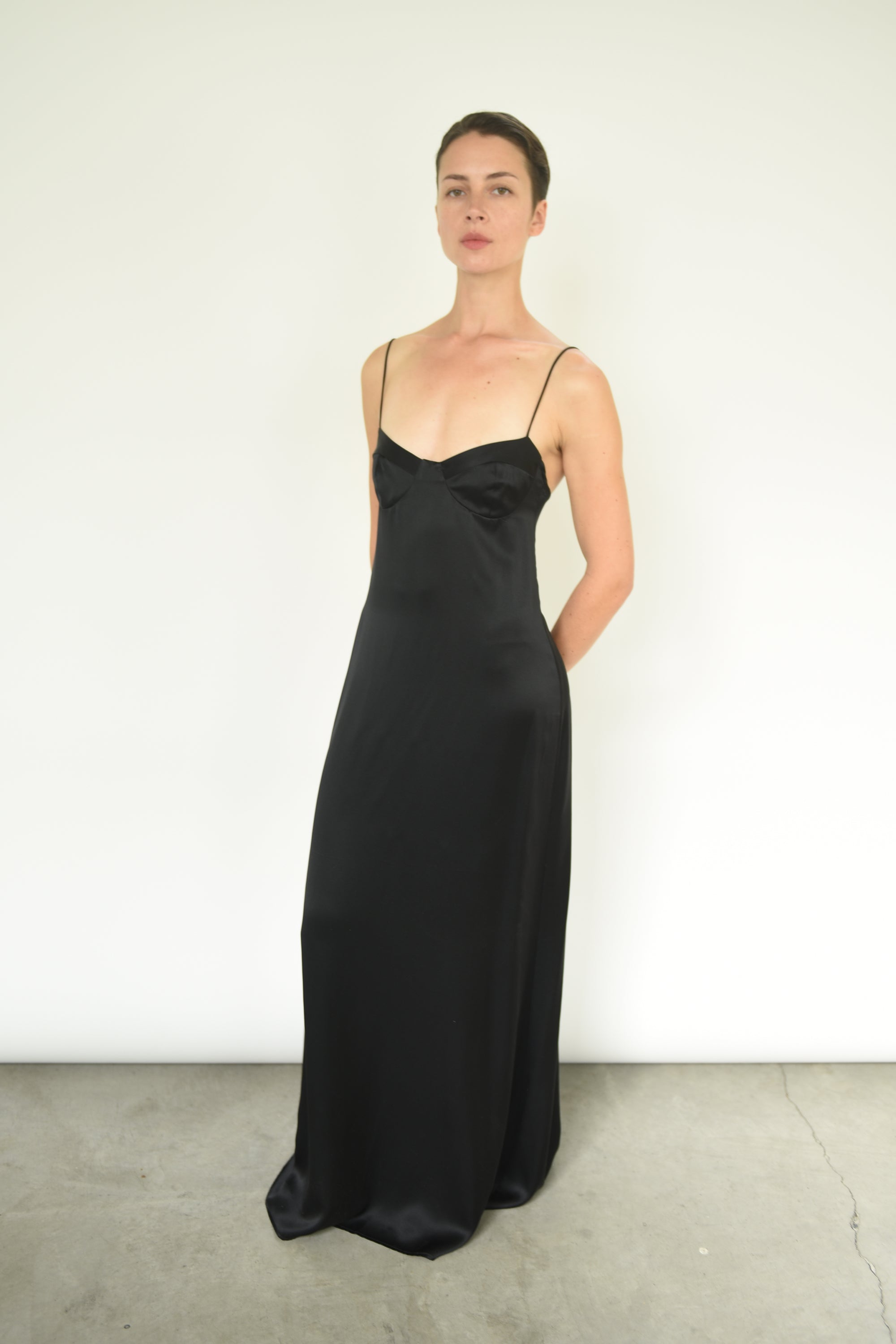 Angled view of the black silk charmeuse Kamperett Sloan Slip with corded straps.