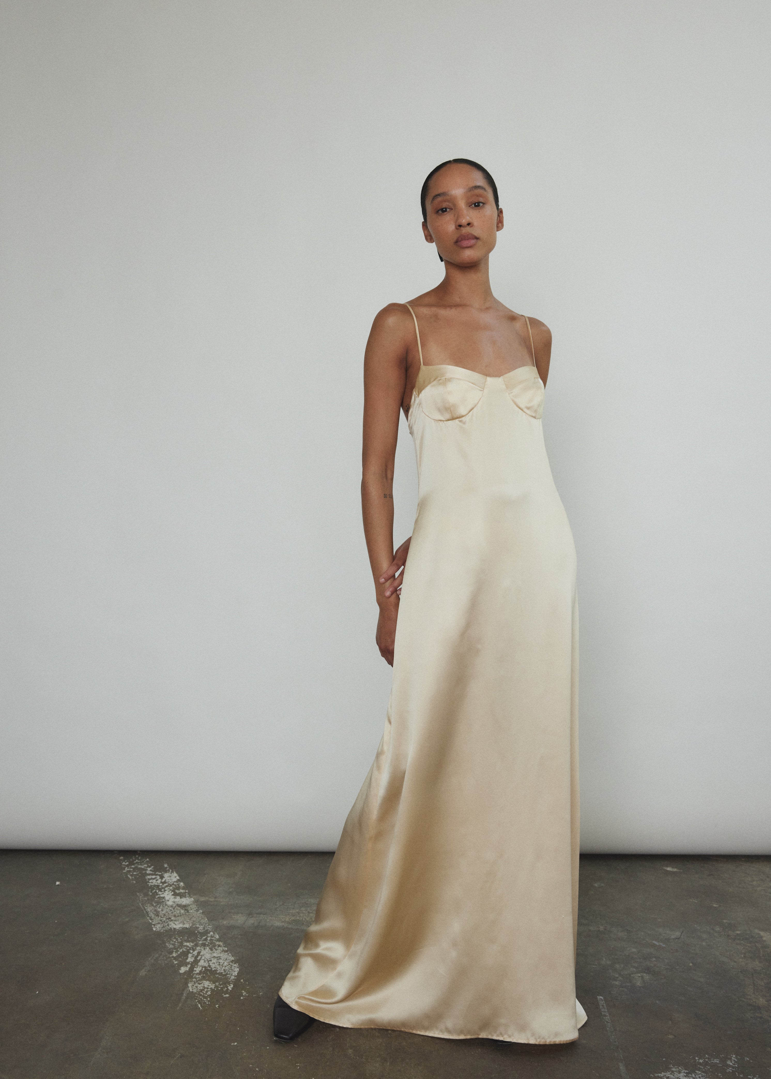 Front view of a bride wearing the champagne silk charmeuse Kamperett Sloan Slip, a maxi-length minimal slip with corded straps.