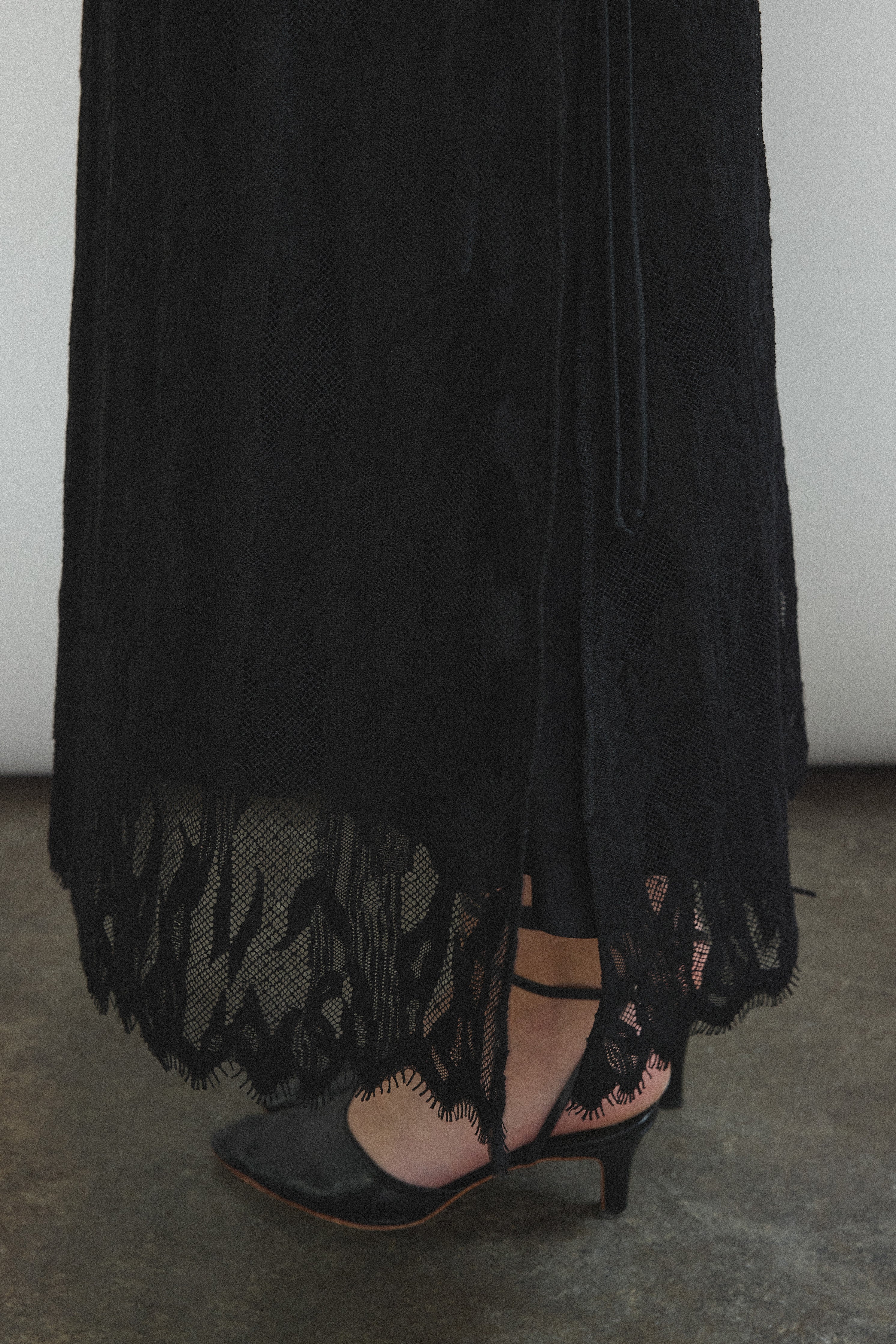 Editorial portrait of a model in the black French lace Kamperett Thea Lace Sheath Dress.