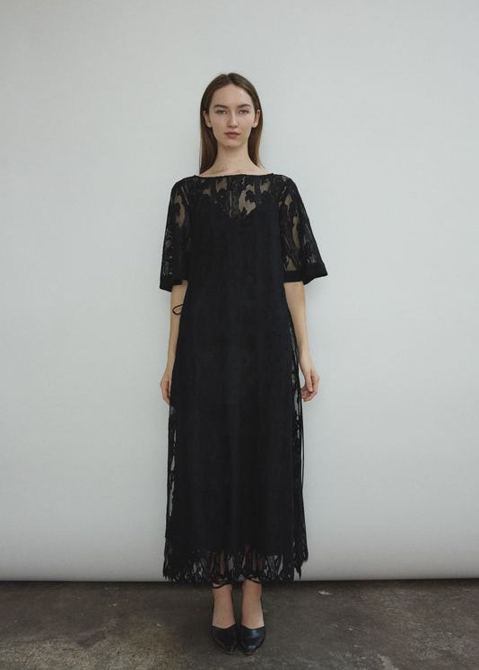 Front view of a model wearing the black French lace Kamperett Thea Lace Sheath Dress, a midi sheath with eyelash lace hem.