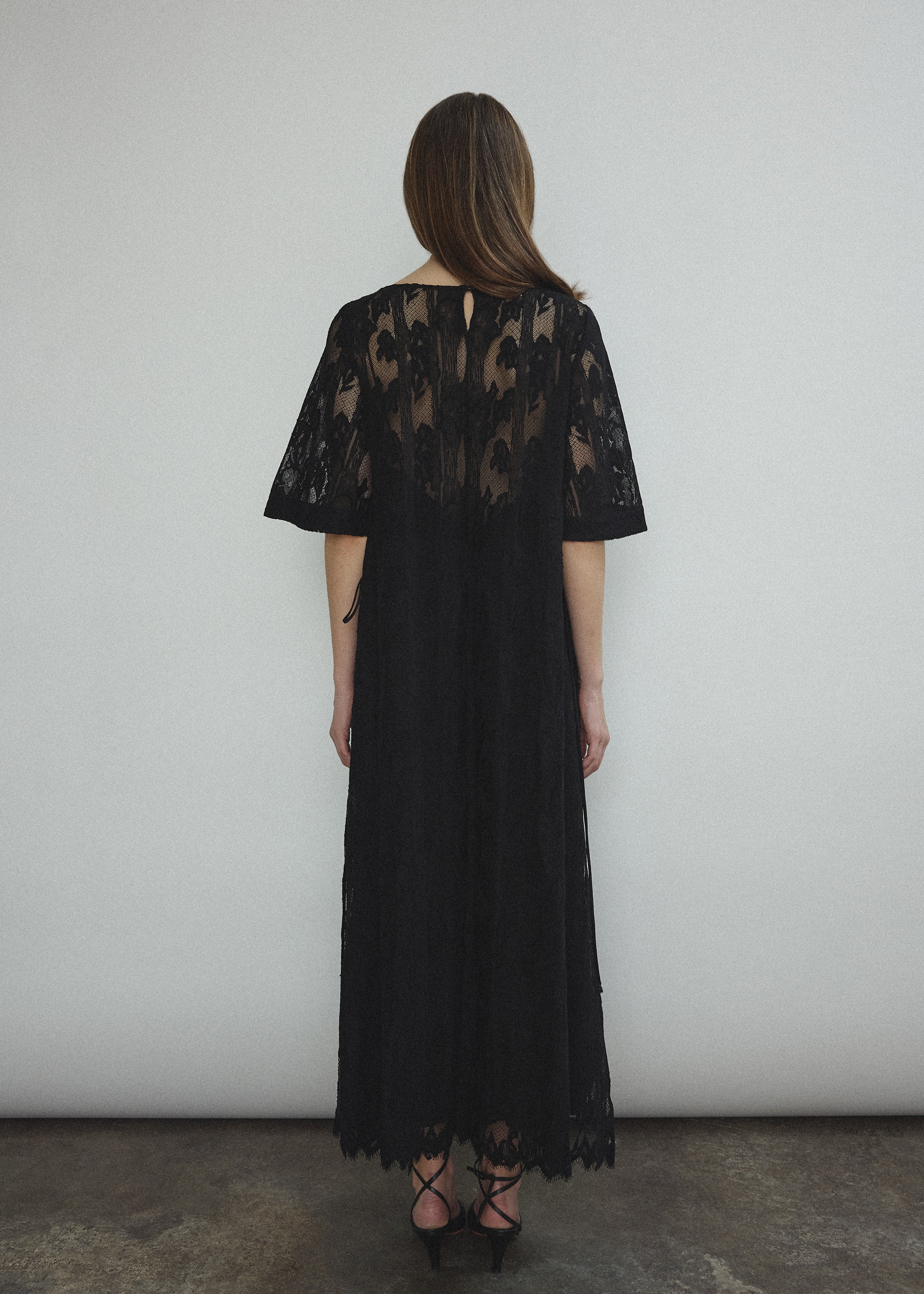 Side view of the black French lace Kamperett Thea Lace Sheath Dress showing the side-tie seams.