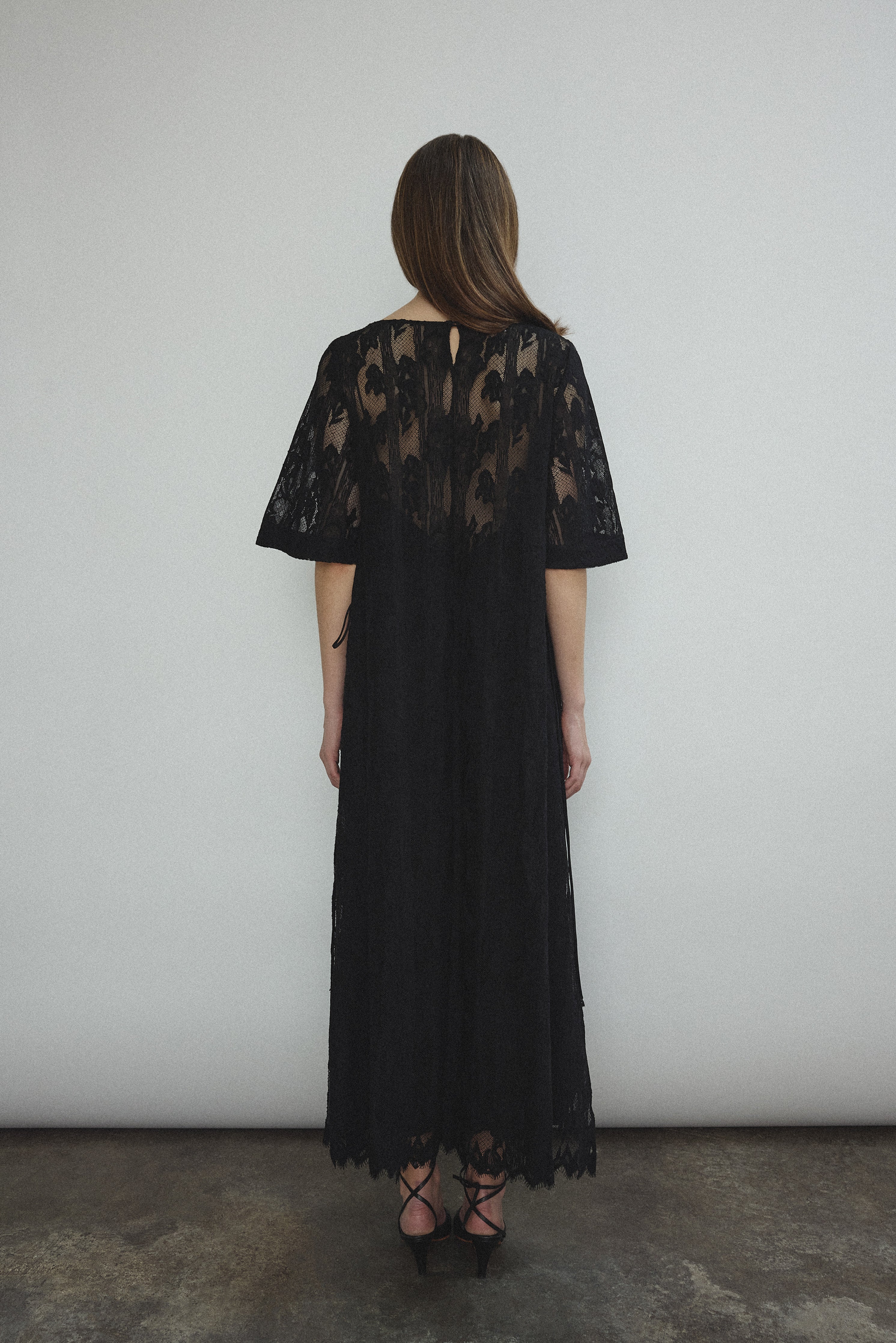 Side view of the black French lace Kamperett Thea Lace Sheath Dress showing the side-tie seams.