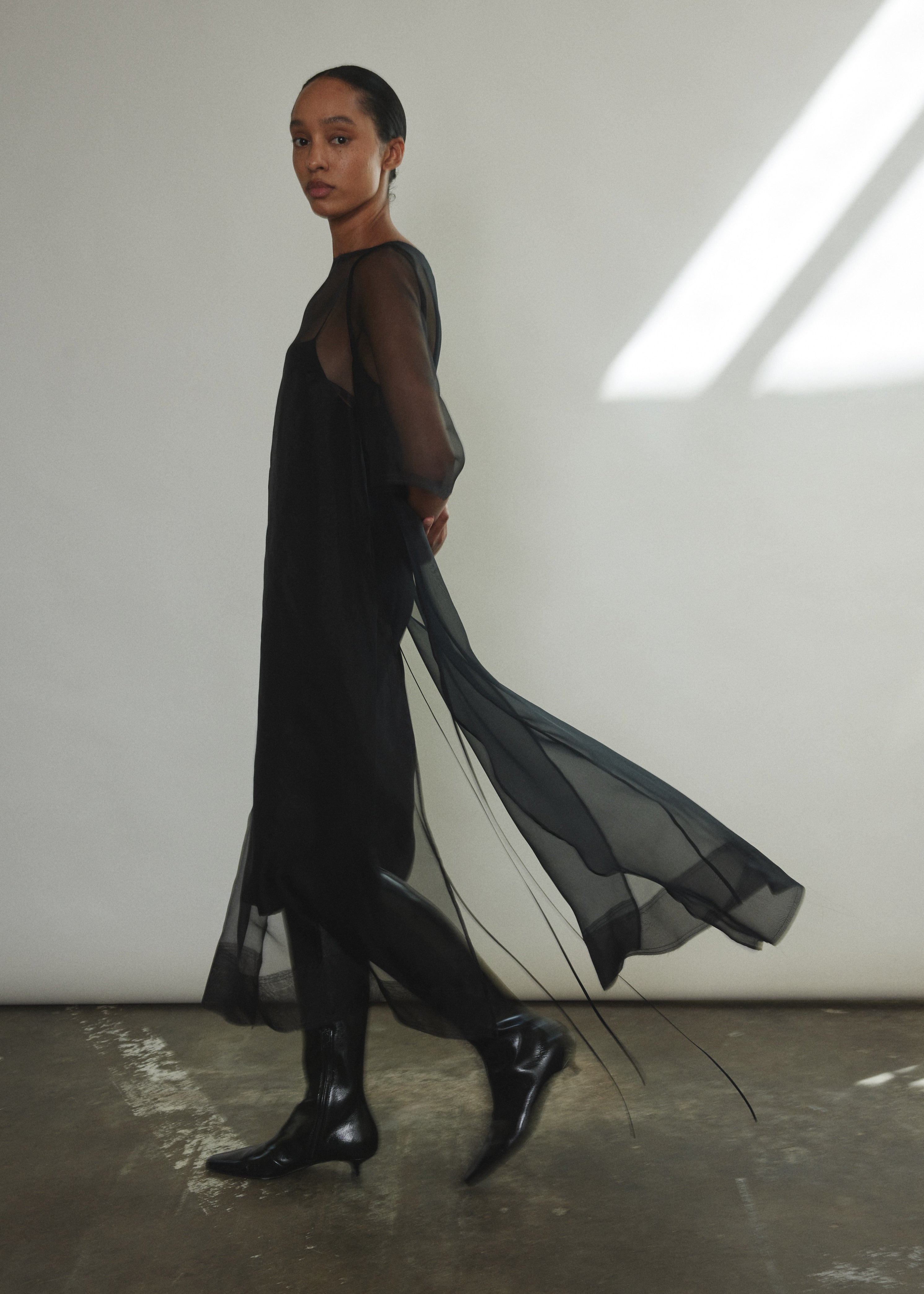 Side view of the black silk organza Kamperett Thea Sheath Dress showing the wide hem facing.