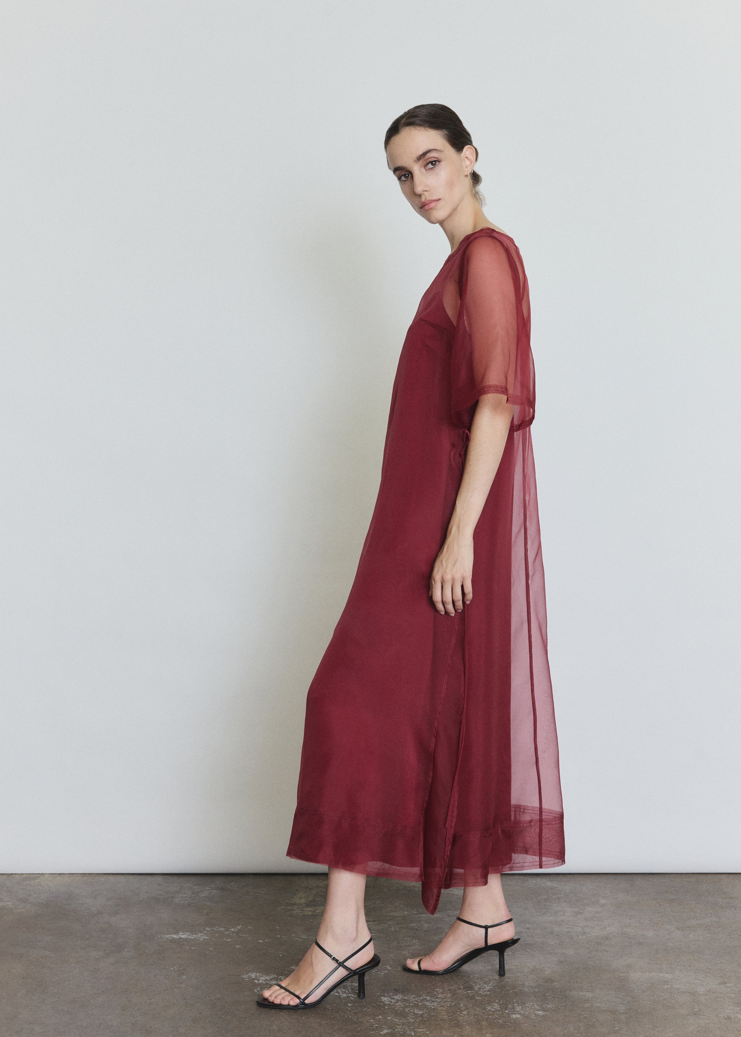 Side view of the bordeaux silk organza Kamperett Thea Sheath Dress showing the open side seams with self corded ties.