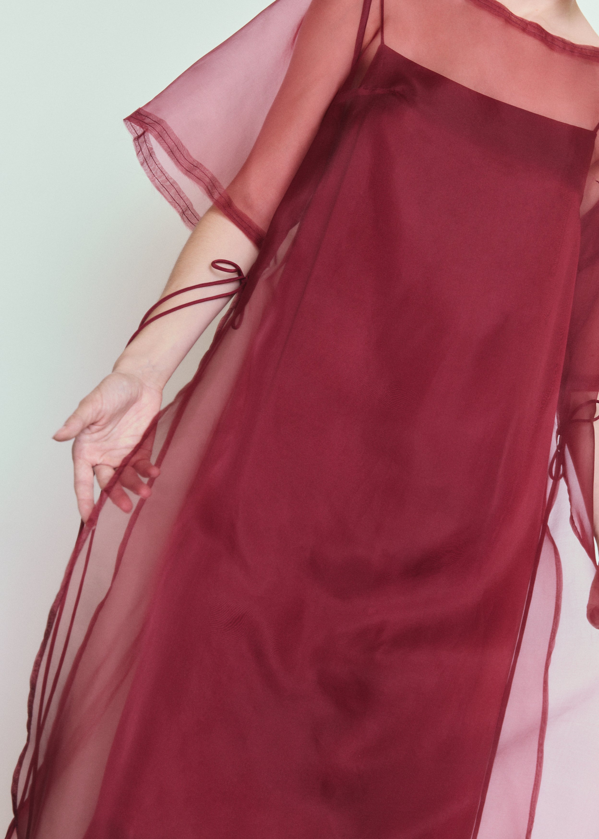 Model wearing the bordeaux Kamperett Thea Sheath Dress layered over the Agnes Slip Dress in Bordeaux.