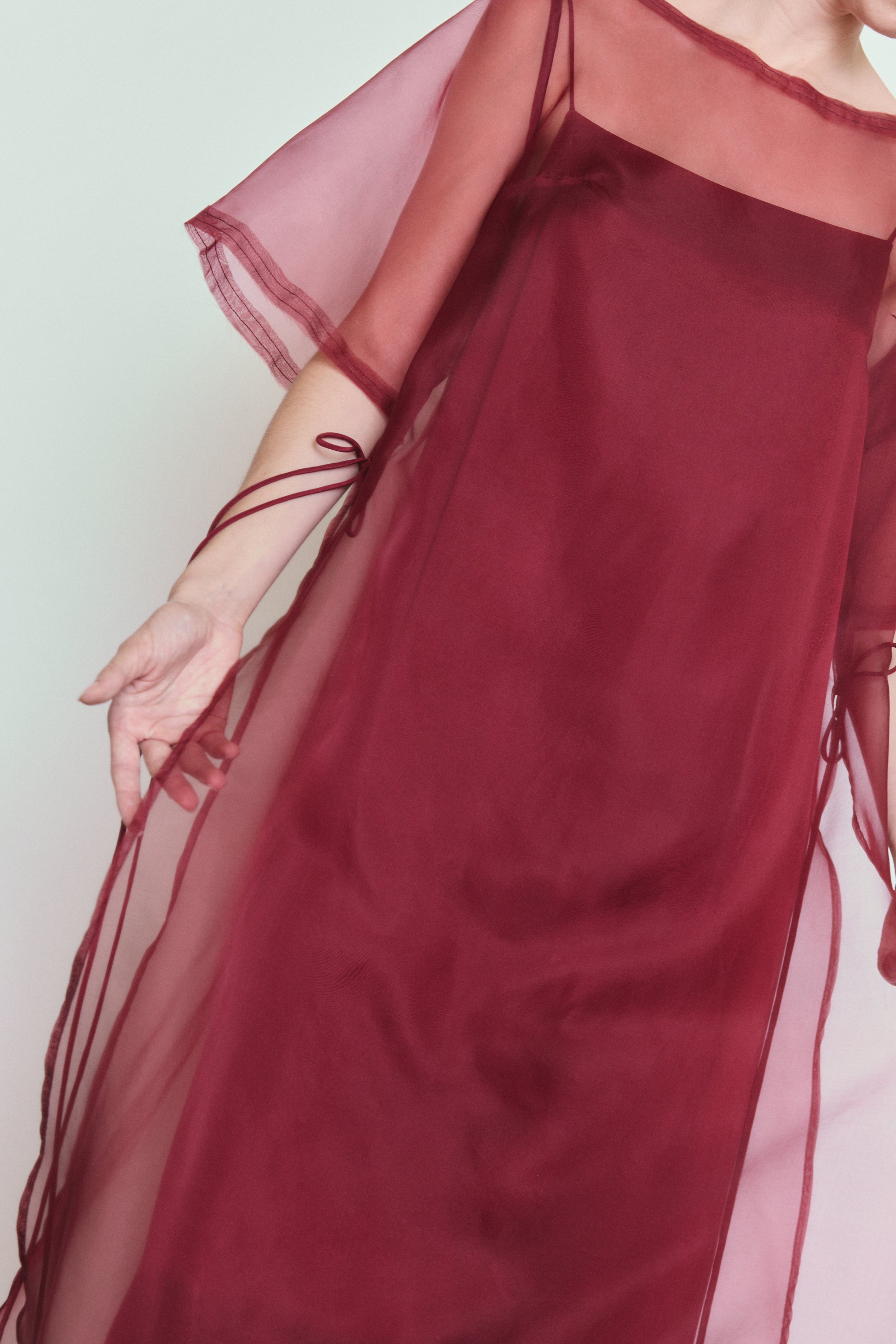 Model wearing the bordeaux Kamperett Thea Sheath Dress layered over the Agnes Slip Dress in Bordeaux.
