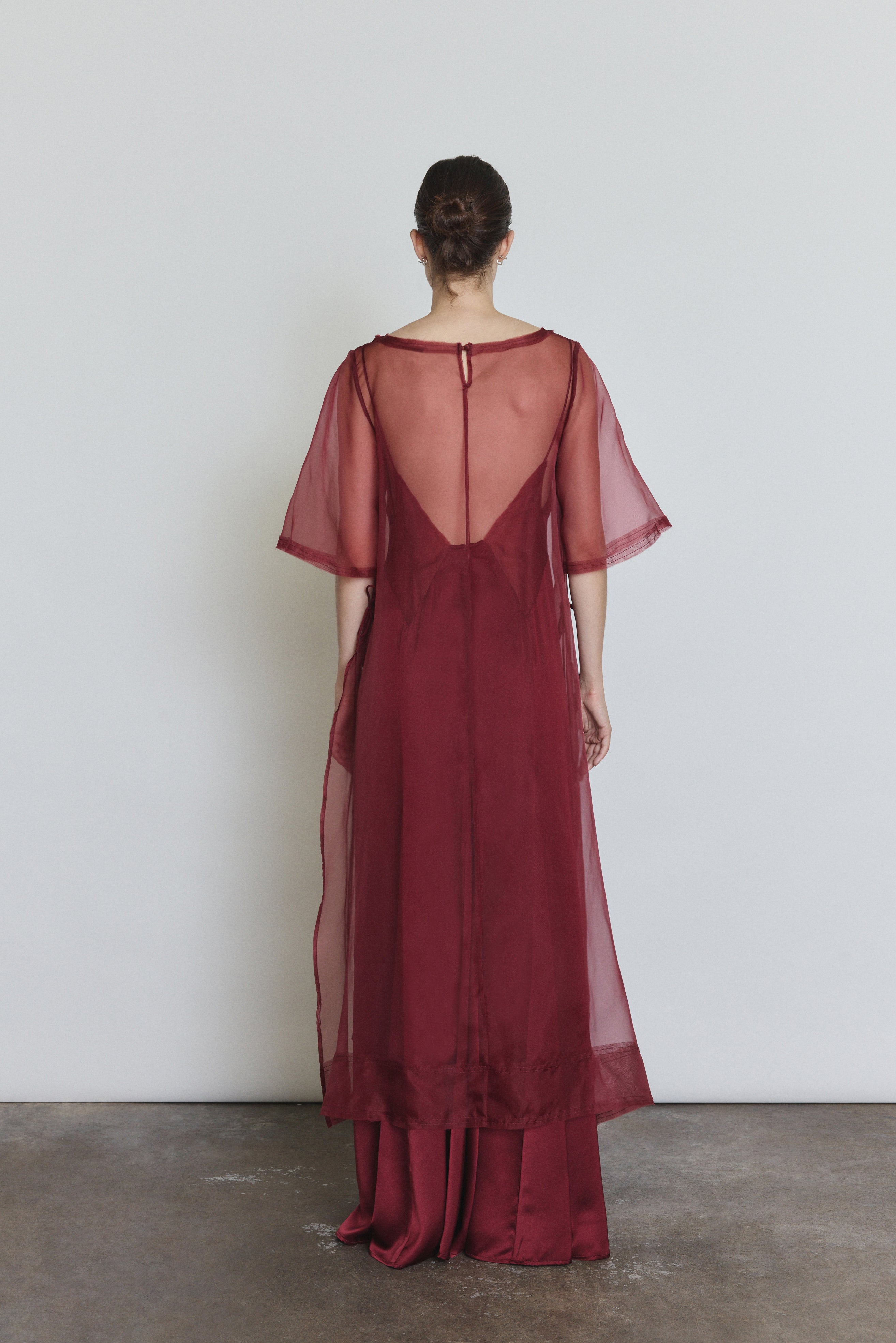 Editorial image of the bordeaux Kamperett Thea Sheath Dress layered over the Simone Slip Dress in Bordeaux.