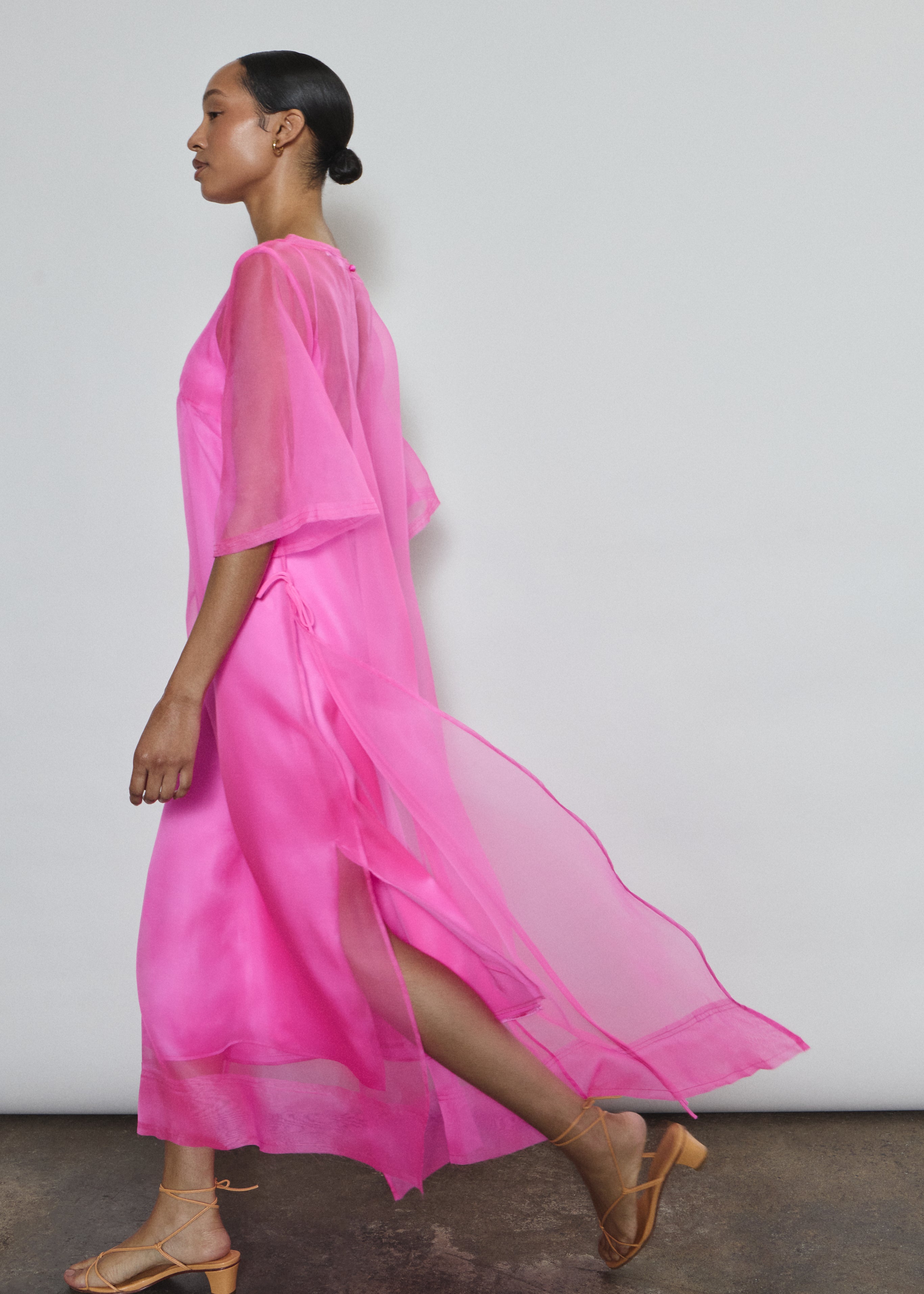 Left profile of hot pink silk organza Thea Sheath Dress. Straight-cut minimalist silhouette glows in saturated silk. Elevated luxury occasion wear, designed in San Francisco.