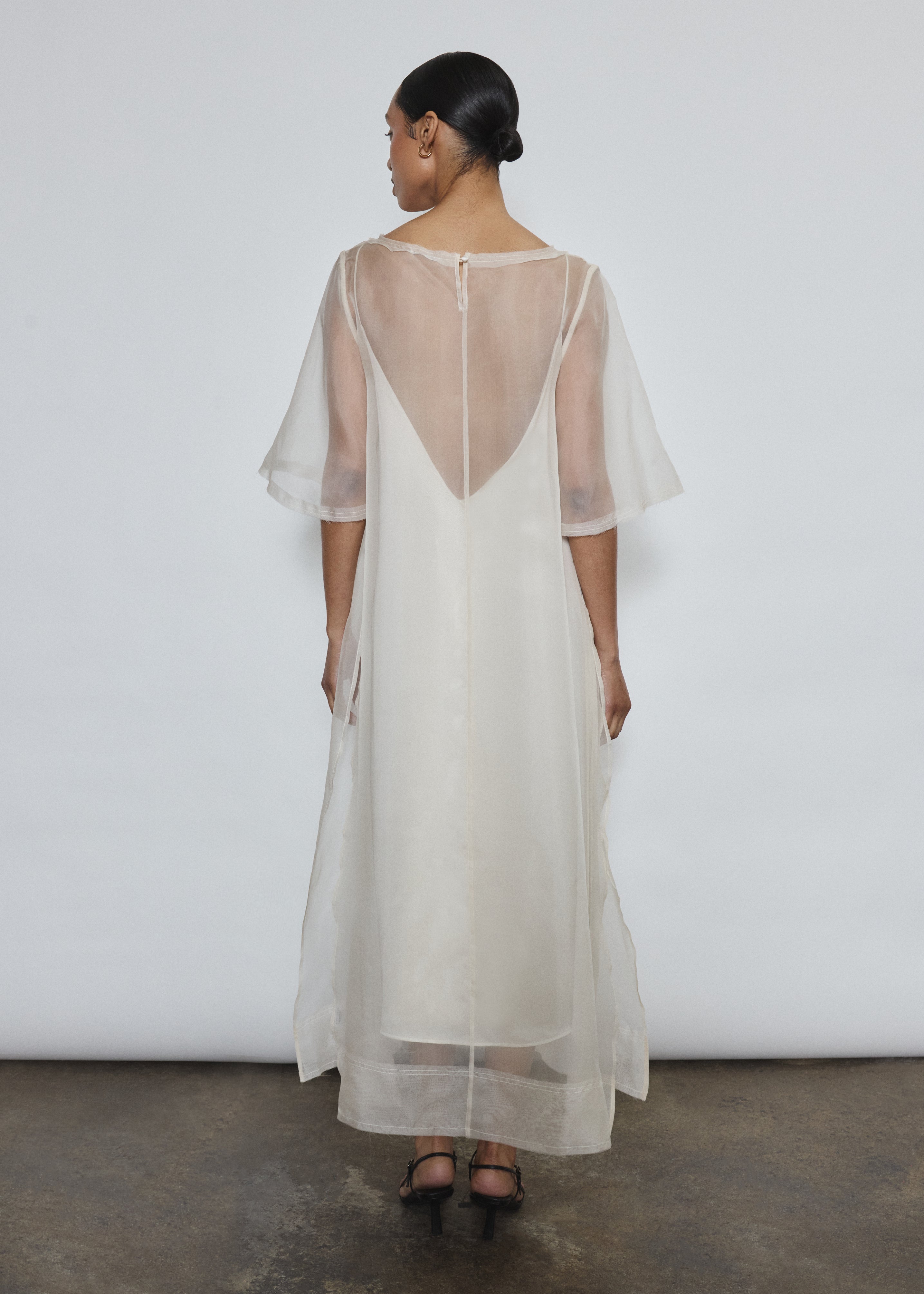 Rear view of ivory silk organza Thea Sheath Dress showing open side seams and wide hem facing. Clean architectural lines, ethically made in California.