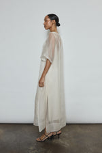 Left profile of ivory silk organza midi dress. Straight-cut minimalist silhouette with raw edge hem. Whisper-weight construction, designed in San Francisco.