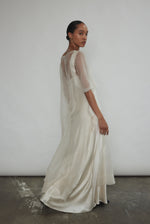 Right profile of Kamperett Thea Sheath Dress in ivory silk organza. Timeless sheath silhouette with sculptural raw edge detailing and self corded ties at the side.