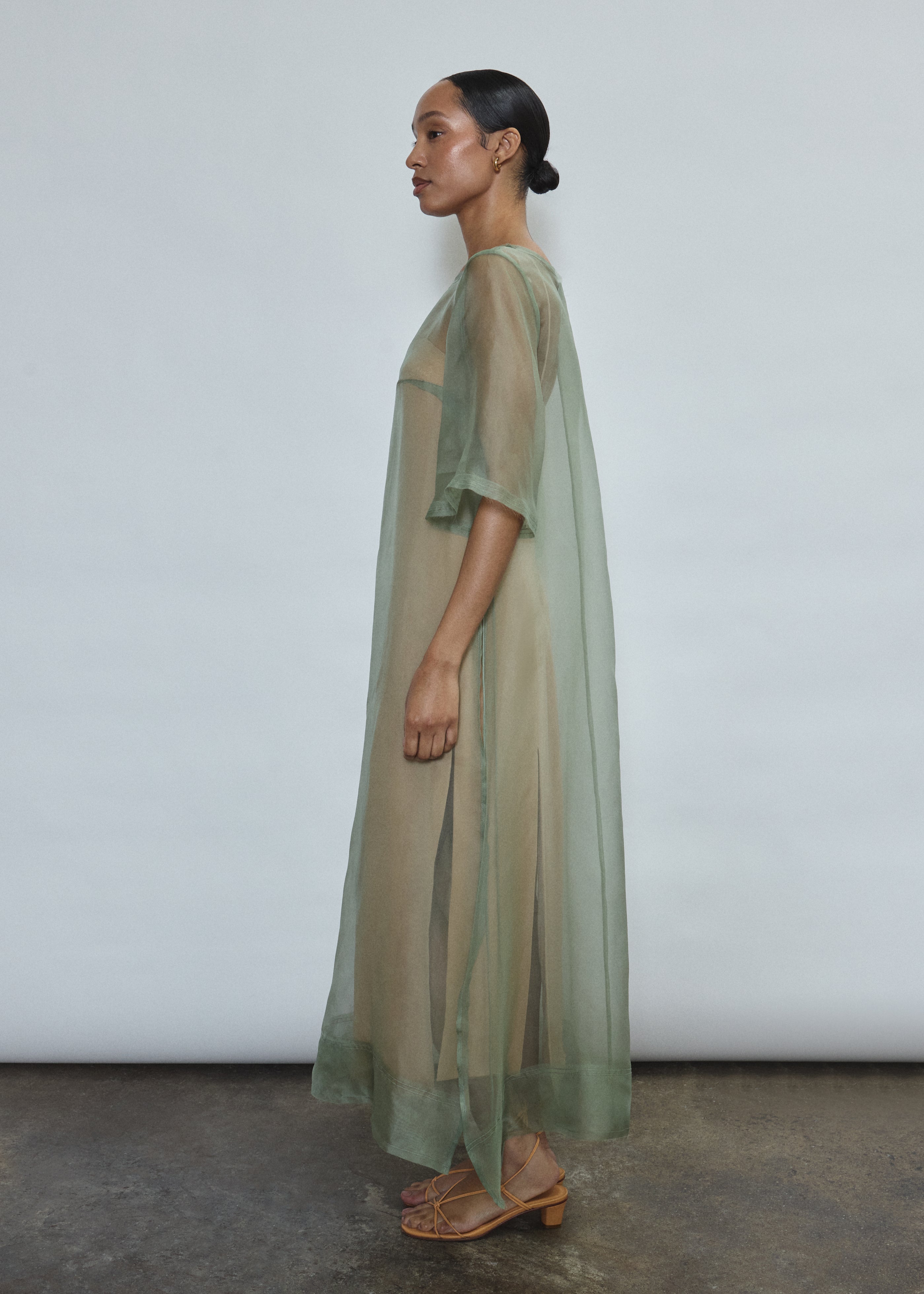 Left profile of jade silk organza Thea Sheath Dress. Straight-cut minimalist silhouette, cool to the touch and luminous in motion. Designed in San Francisco.