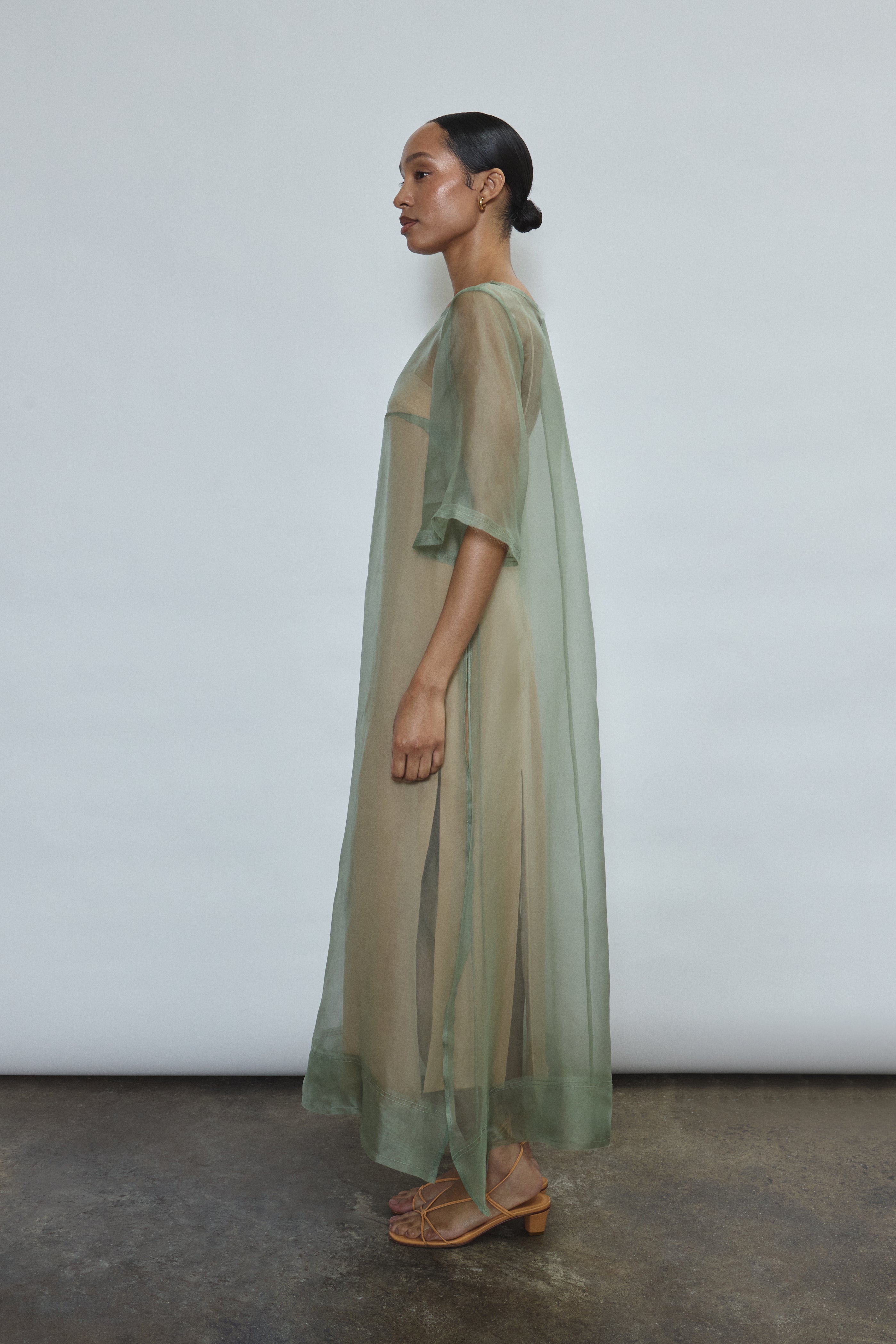 Left profile of jade silk organza Thea Sheath Dress. Straight-cut minimalist silhouette, cool to the touch and luminous in motion. Designed in San Francisco.