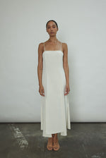 Front view of a bride wearing the alabaster silk crepe Kamperett Theodora Dress, a midi slip with multi-slit hemline.