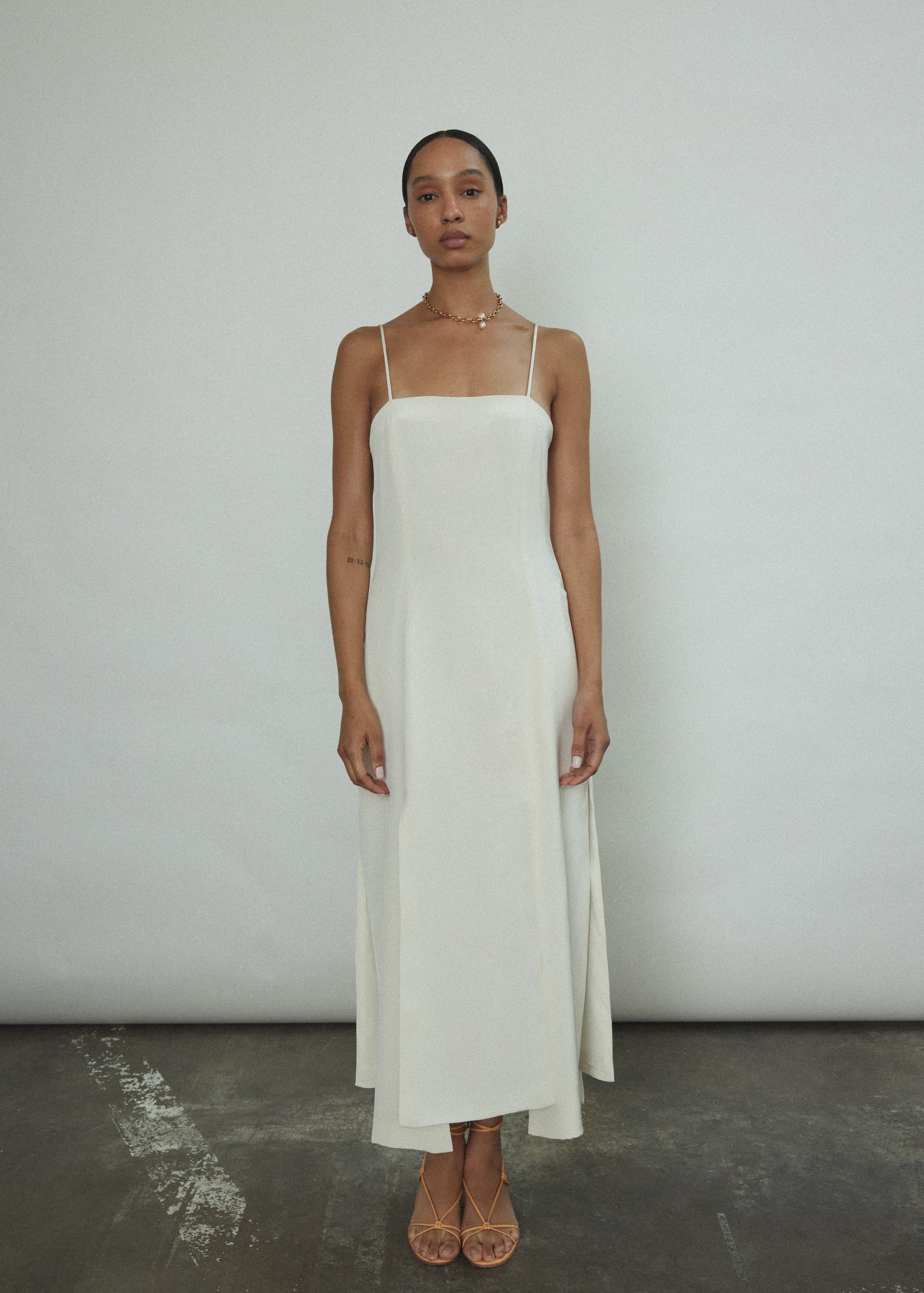 Front view of a bride wearing the alabaster silk crepe Kamperett Theodora Dress, a midi slip with multi-slit hemline.