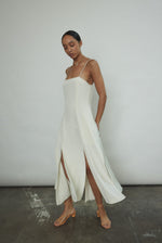 Side view of the alabaster silk crepe Kamperett Theodora Dress showing the multi-slit hemline.