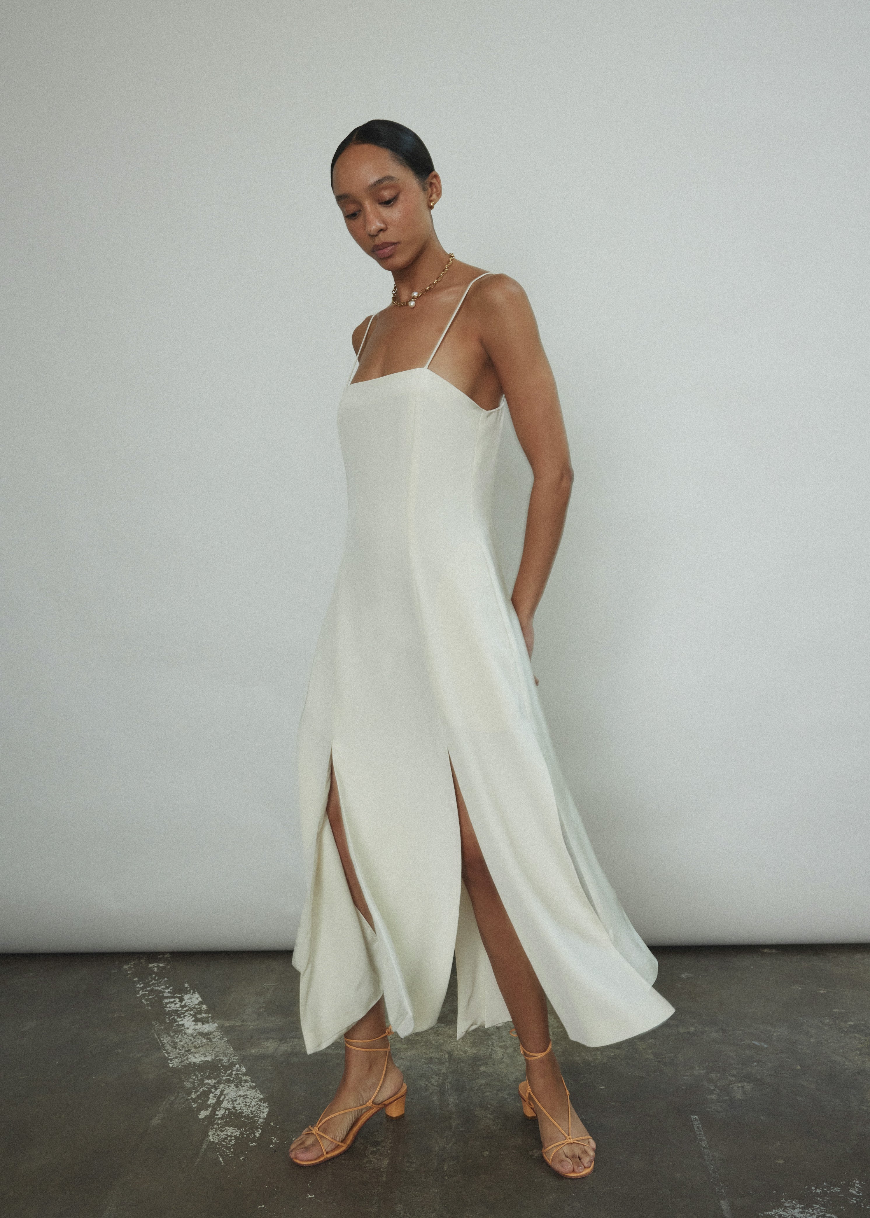 Side view of the alabaster silk crepe Kamperett Theodora Dress showing the multi-slit hemline.