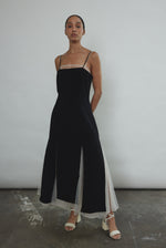 Front view of a model wearing the black crepe Kamperett Theodora Dress, a midi slip with multi-slit hemline.