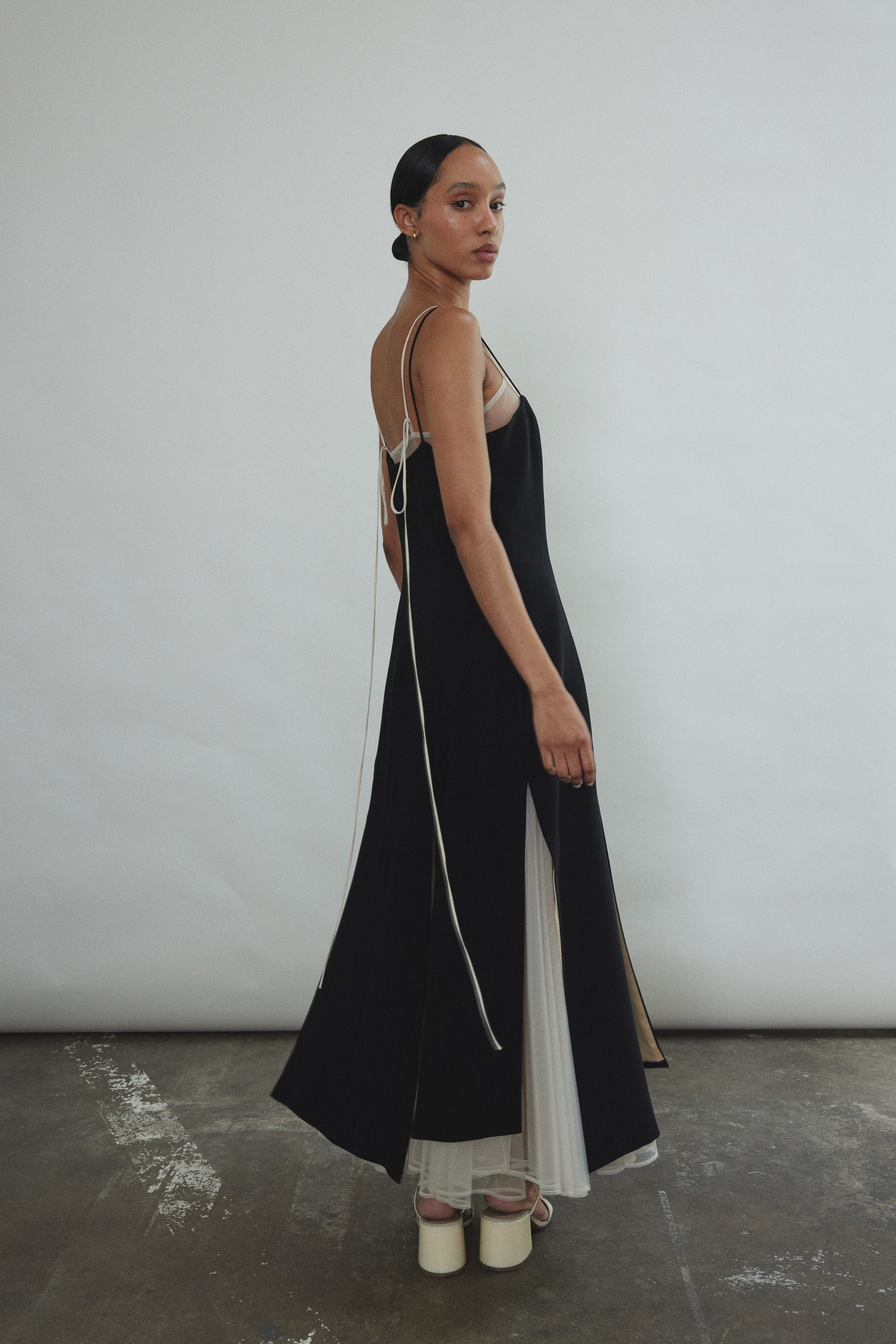 Detail of the multi-slit hemline on the black crepe Kamperett Theodora Dress.