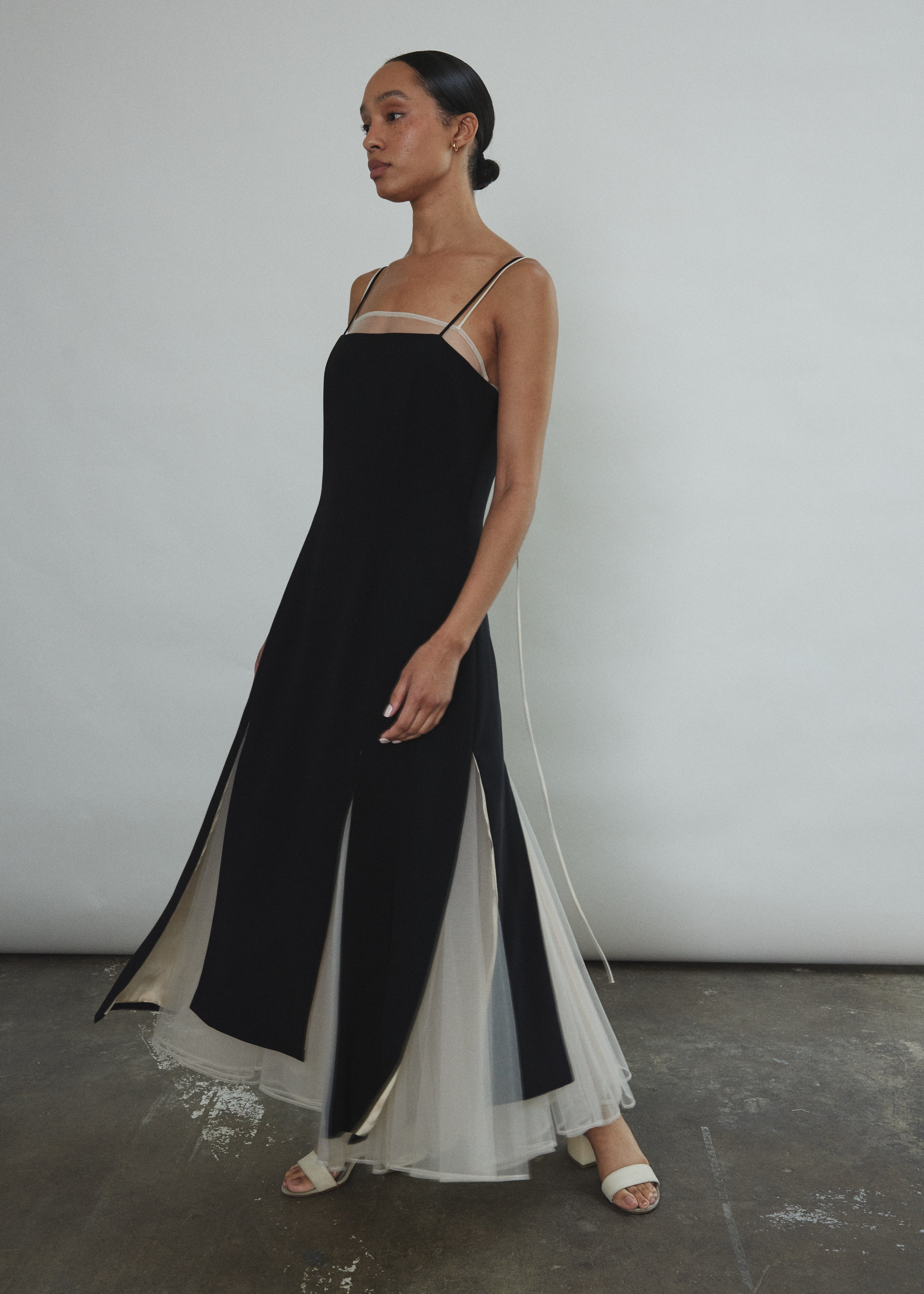 Side view of the black crepe Kamperett Theodora Dress showing the multi-slit hemline.