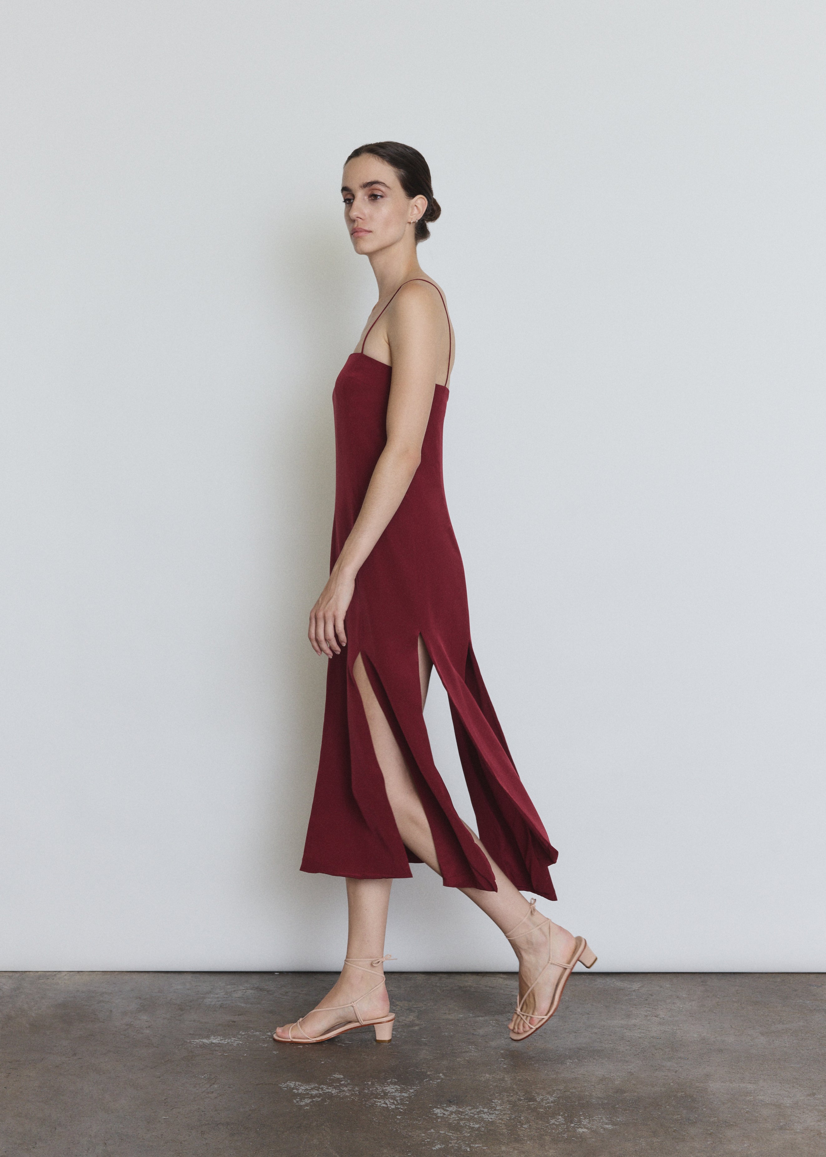 Detail of the bordeaux silk Kamperett Theodora Dress showing the multi-slit hem construction.