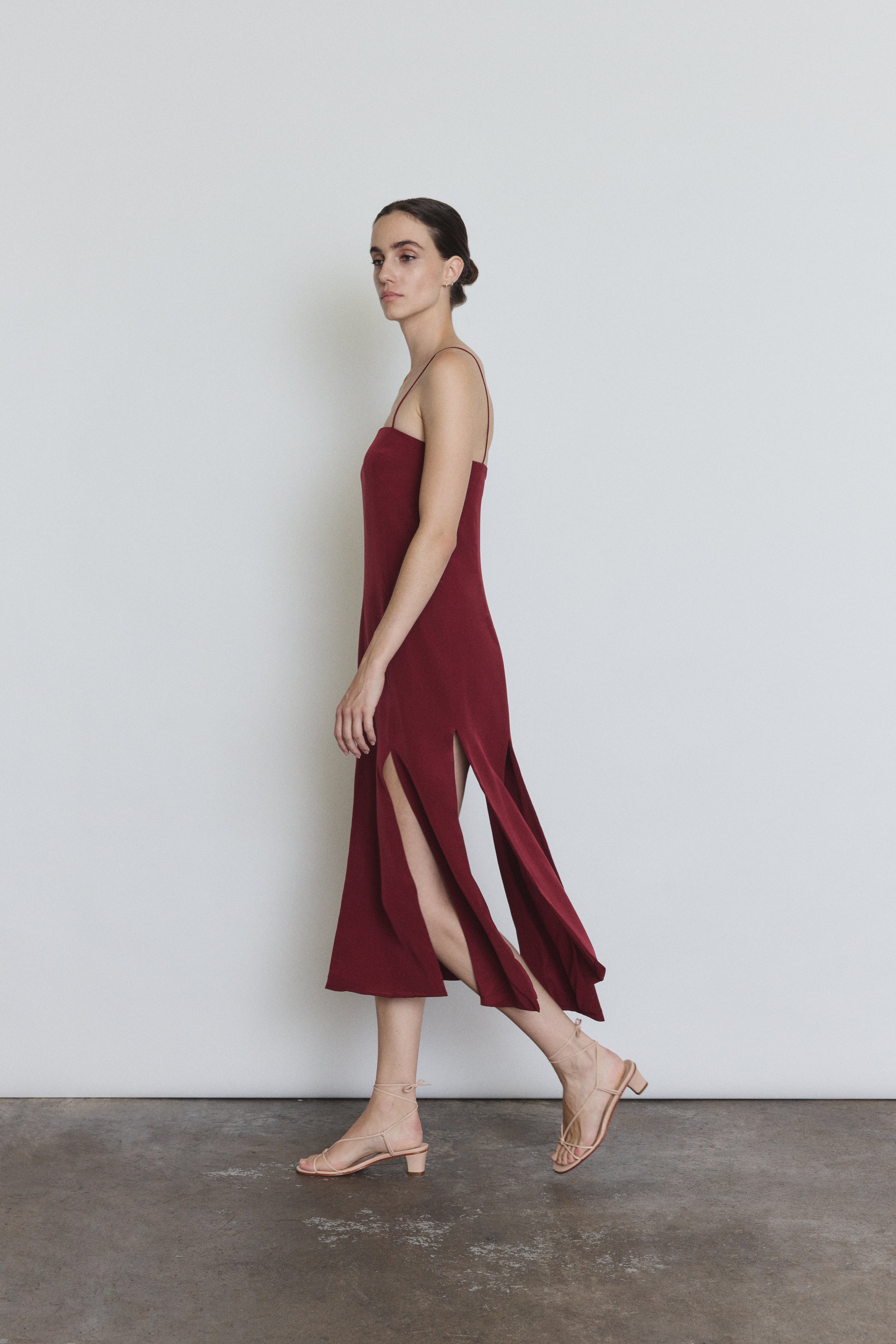 Detail of the bordeaux silk Kamperett Theodora Dress showing the multi-slit hem construction.