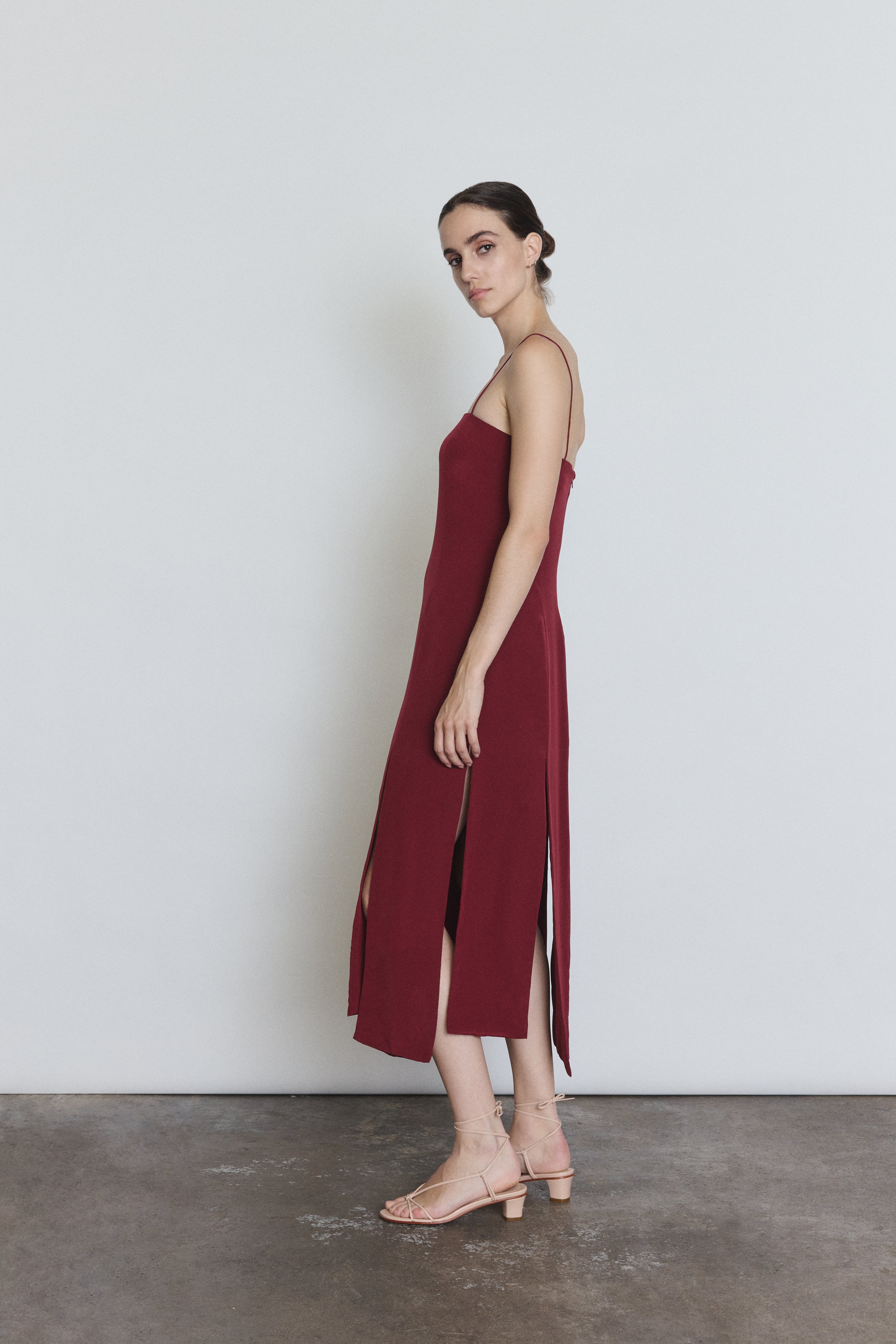 Side view of the bordeaux silk Kamperett Theodora Dress showing the straight-cut silhouette.