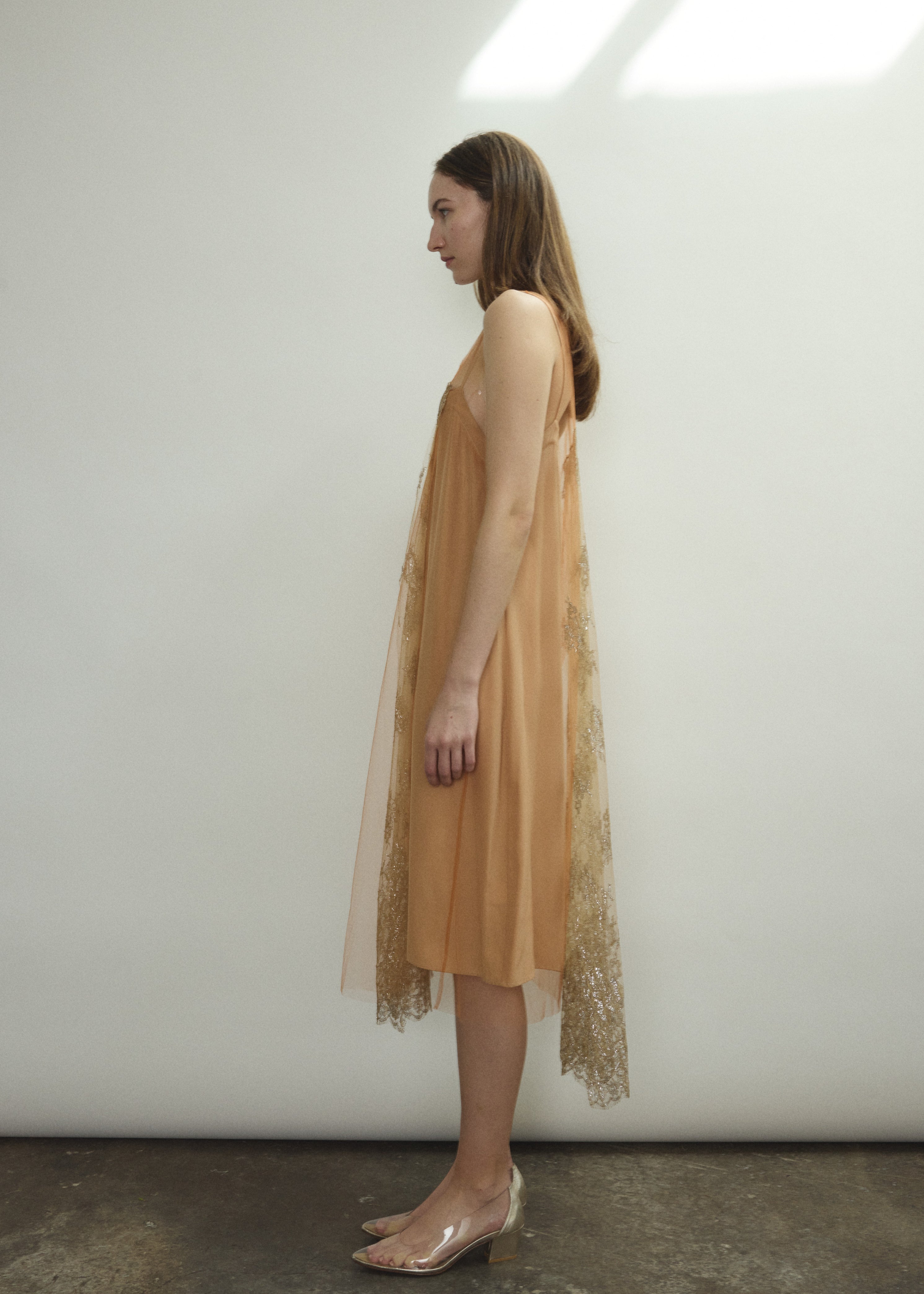 Left profile of Kamperett Thistle Lace Shift in persimmon — effortless A-line silhouette in delicate French lace tulle, sleeveless, minimalist occasion dress.