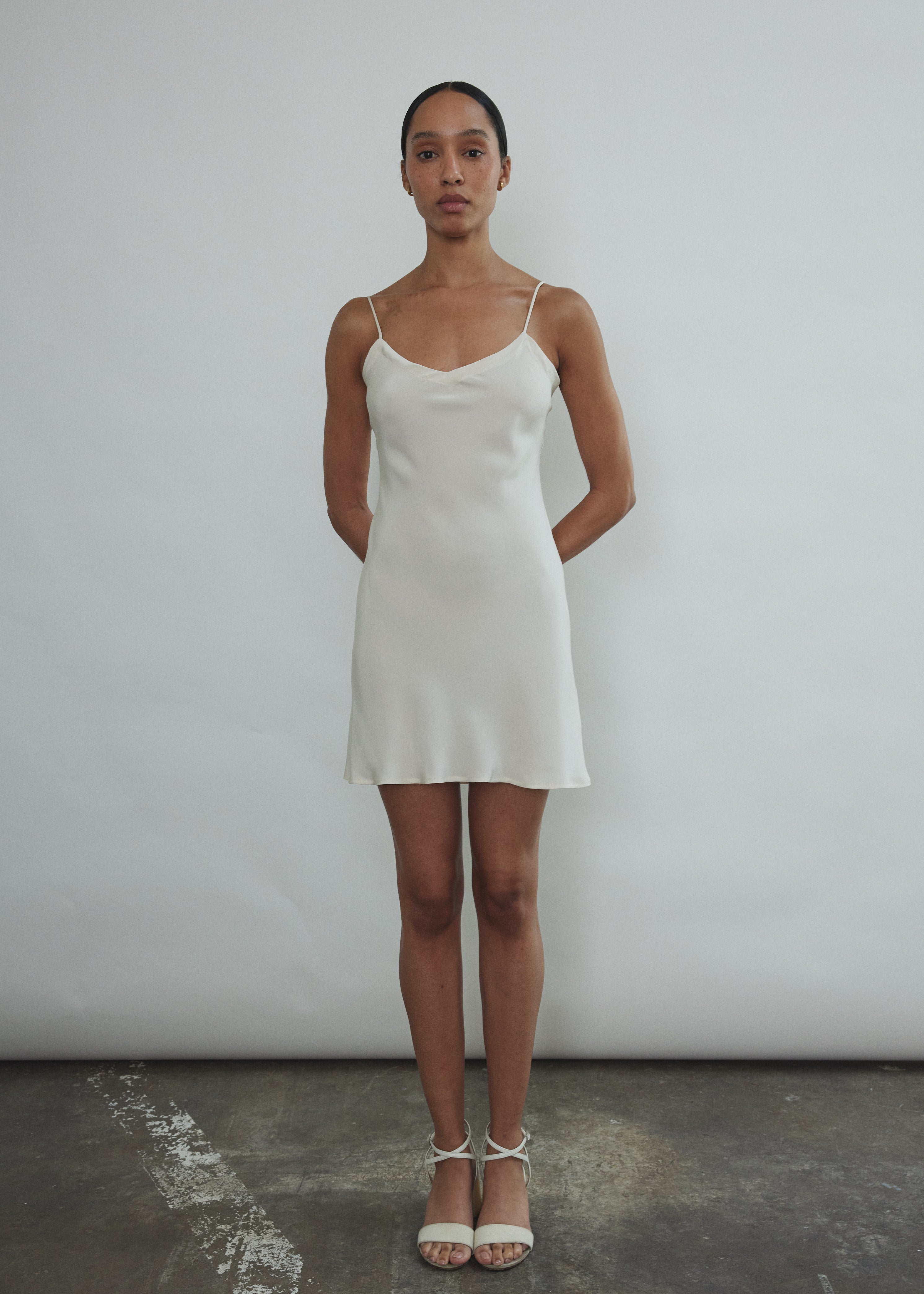 Front view of a bride wearing the ivory silk Kamperett V-Neck Mini Slip, a bias-cut mini with V-neckline.
