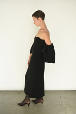 Angled view of the black crepe Kamperett Verona Midi Dress, showing the off-shoulder neckline and full draped sleeves.