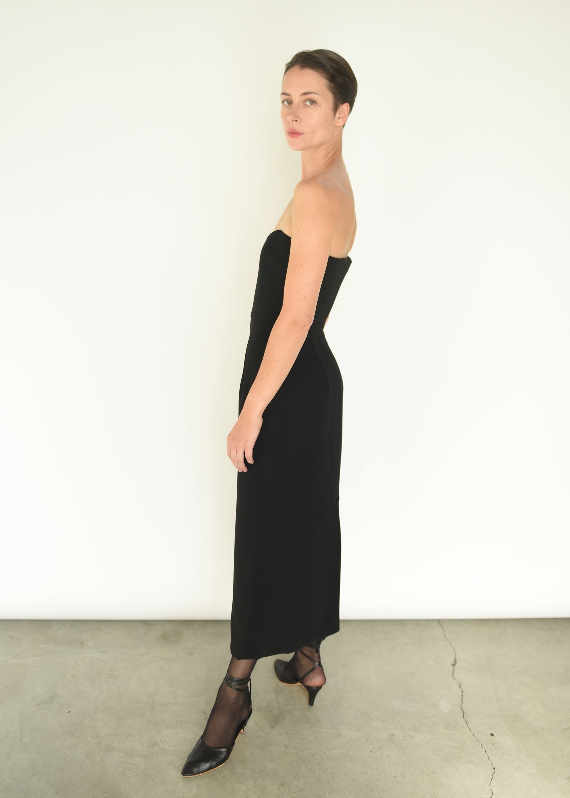 Side view of the black crepe Kamperett Verona Midi Dress with column silhouette and waist seaming.