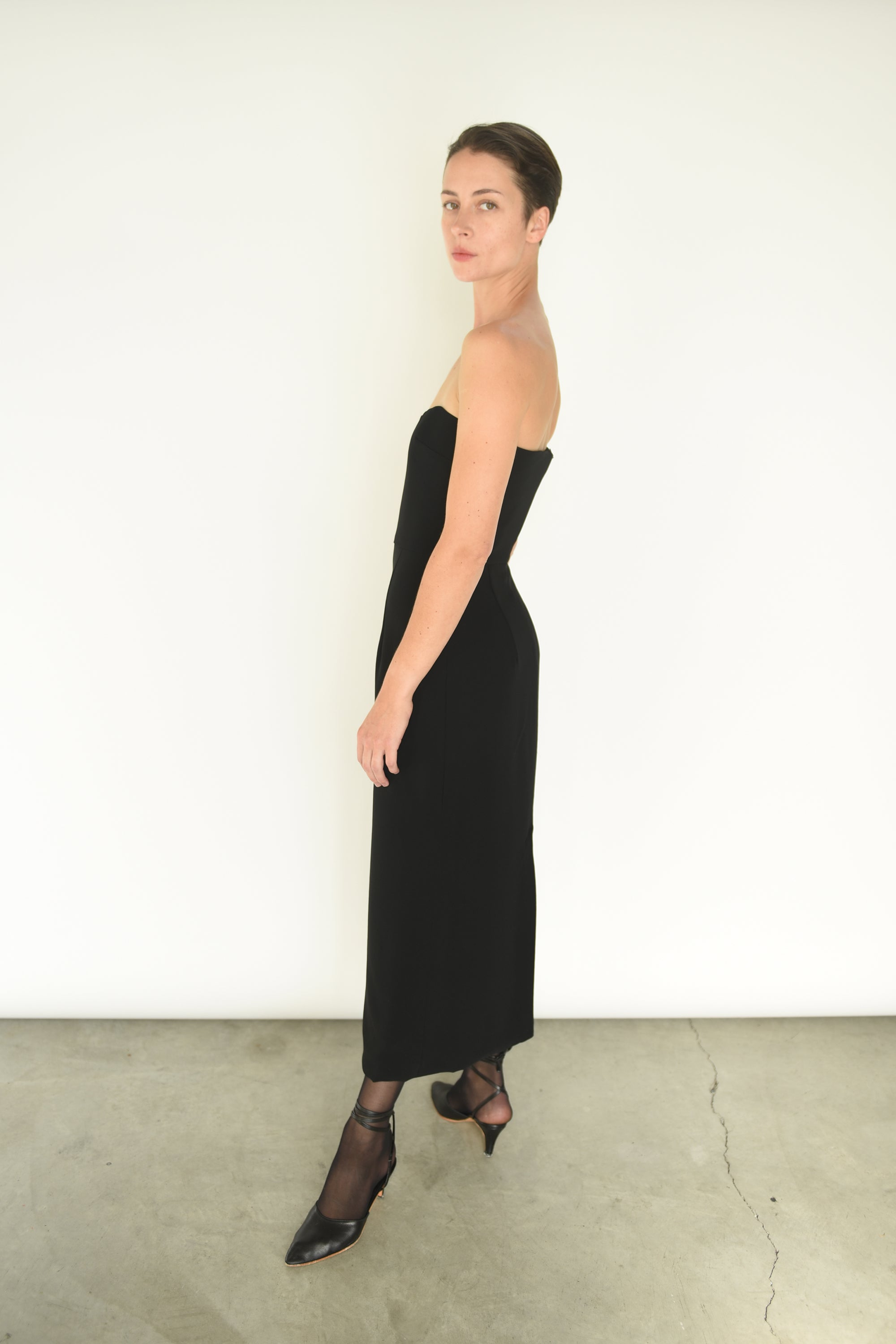 Side view of the black crepe Kamperett Verona Midi Dress with column silhouette and waist seaming.