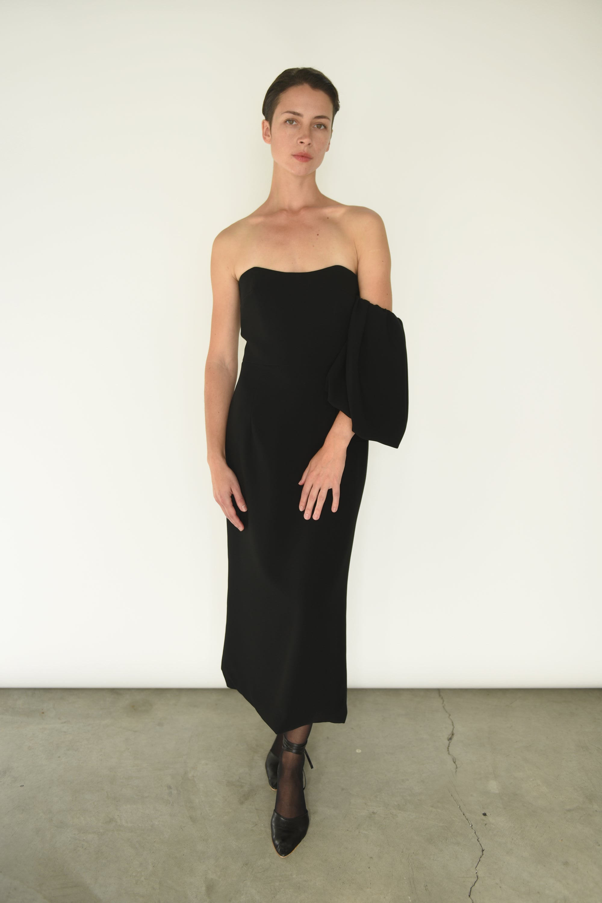 The black crepe Kamperett Verona Midi Dress shown with sleeves detached, revealing the column silhouette.