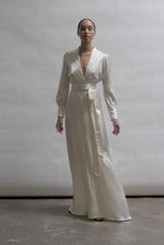 Full-length view of a bride wearing the ivory silk charmeuse Adelaide wrap gown, featuring voluminous sleeves with button cuffs and a plunging neckline.
