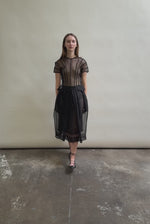 Model wearing the Black silk organza Brise Skirt, showcasing its voluminous silhouette, sheer fabric, and elegant midi-length drape.