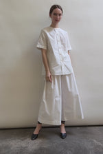 Model wearing the Kamperett Alix Pant in White, featuring a high-waisted wide-leg silhouette in crisp Japanese cotton lawn with deep side pockets.
