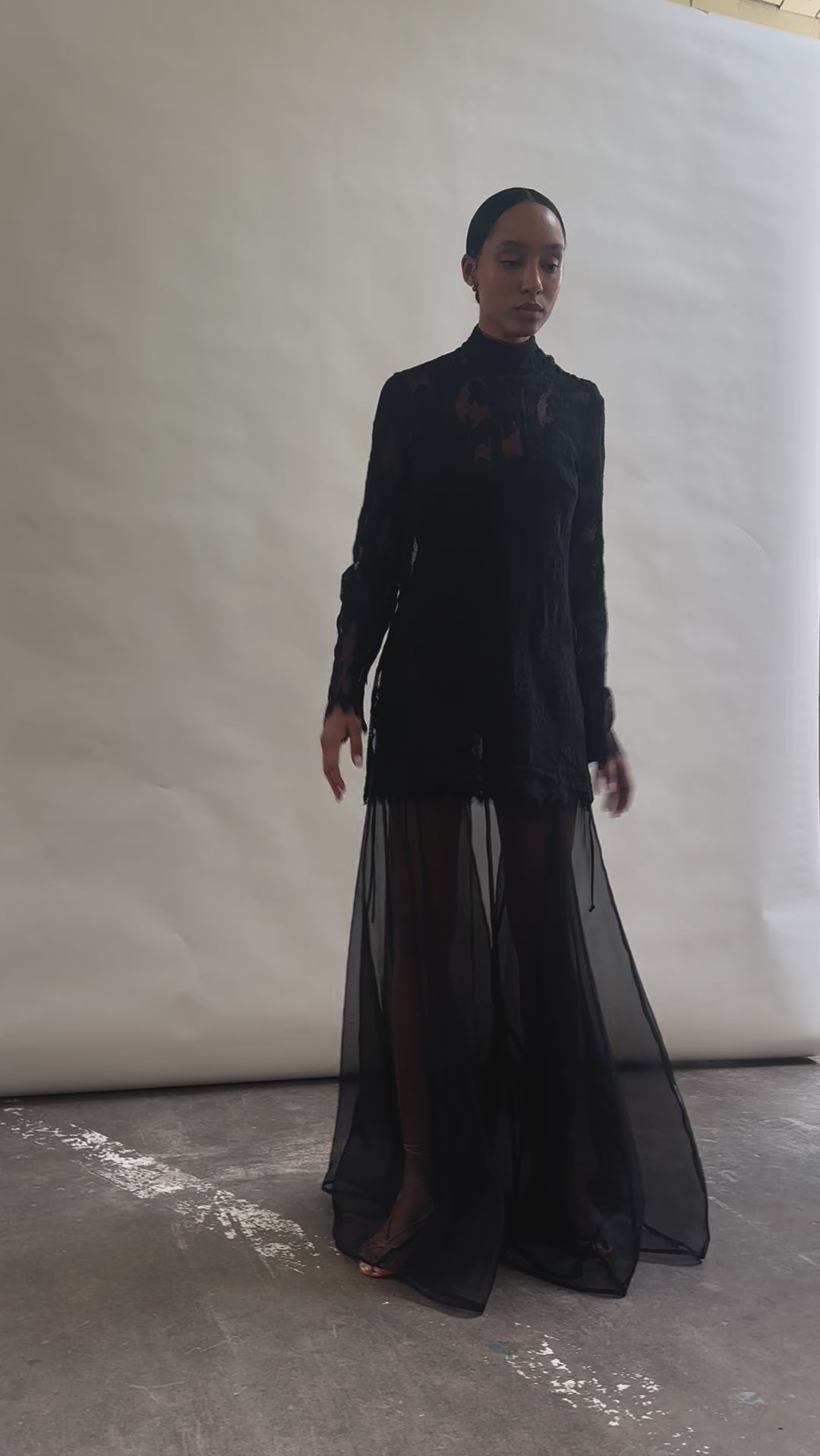 Kamperett Isabella Tunic in black lace mid-movement, silk cord ties flowing at sides, eyelash hem lifting softly, capturing the fluid drape of unlined French lace fabric.