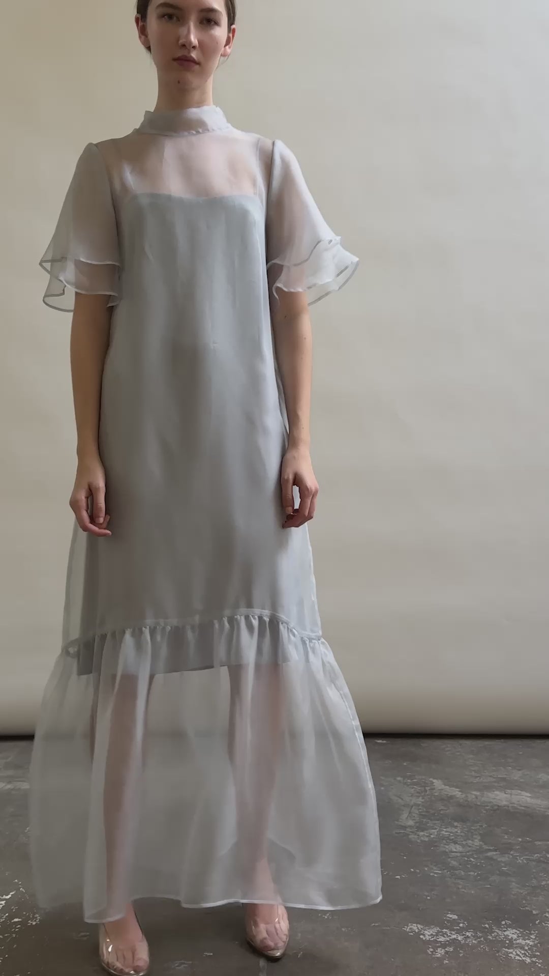 Model in a voluminous blue silk organza Barre maxi dress with oversized ruffles and tiered sleeves.