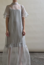 Model in a voluminous blue silk organza Barre maxi dress with oversized ruffles and tiered sleeves.